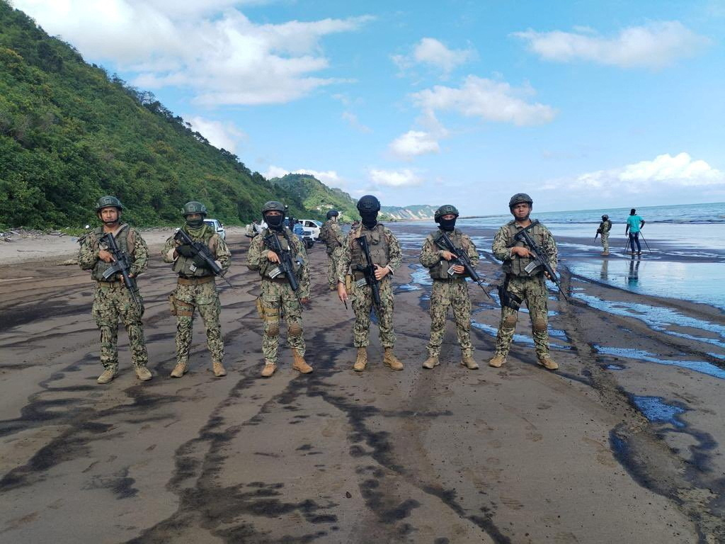 Soldiers stand guard at the site of an oil spill