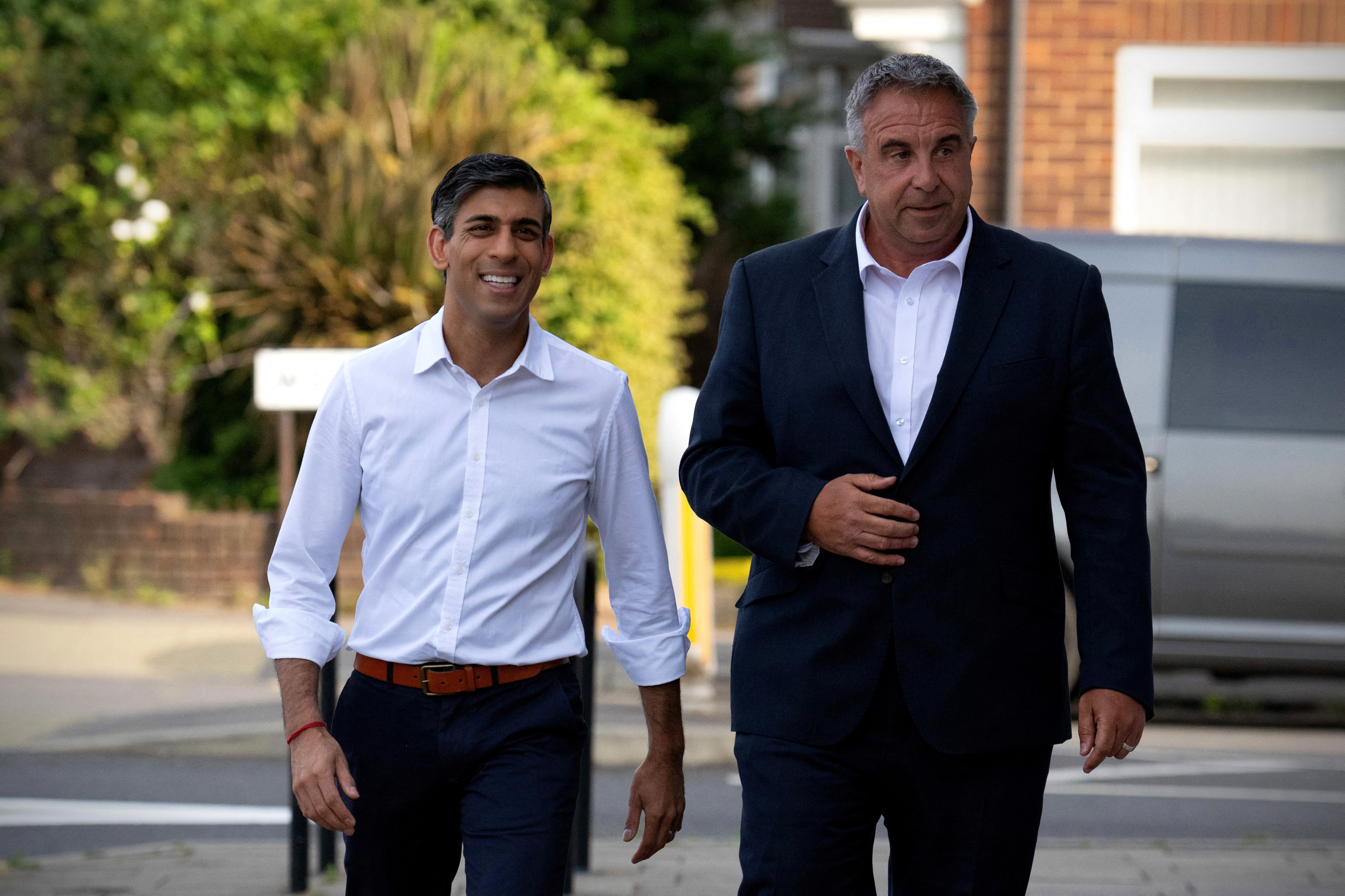 Britain's Prime Minister, Rishi Sunak (L), walks with the new Conservative Party MP for Uxbridge and South Ruislip, Steve Tuckwell, following his win in the local by-election