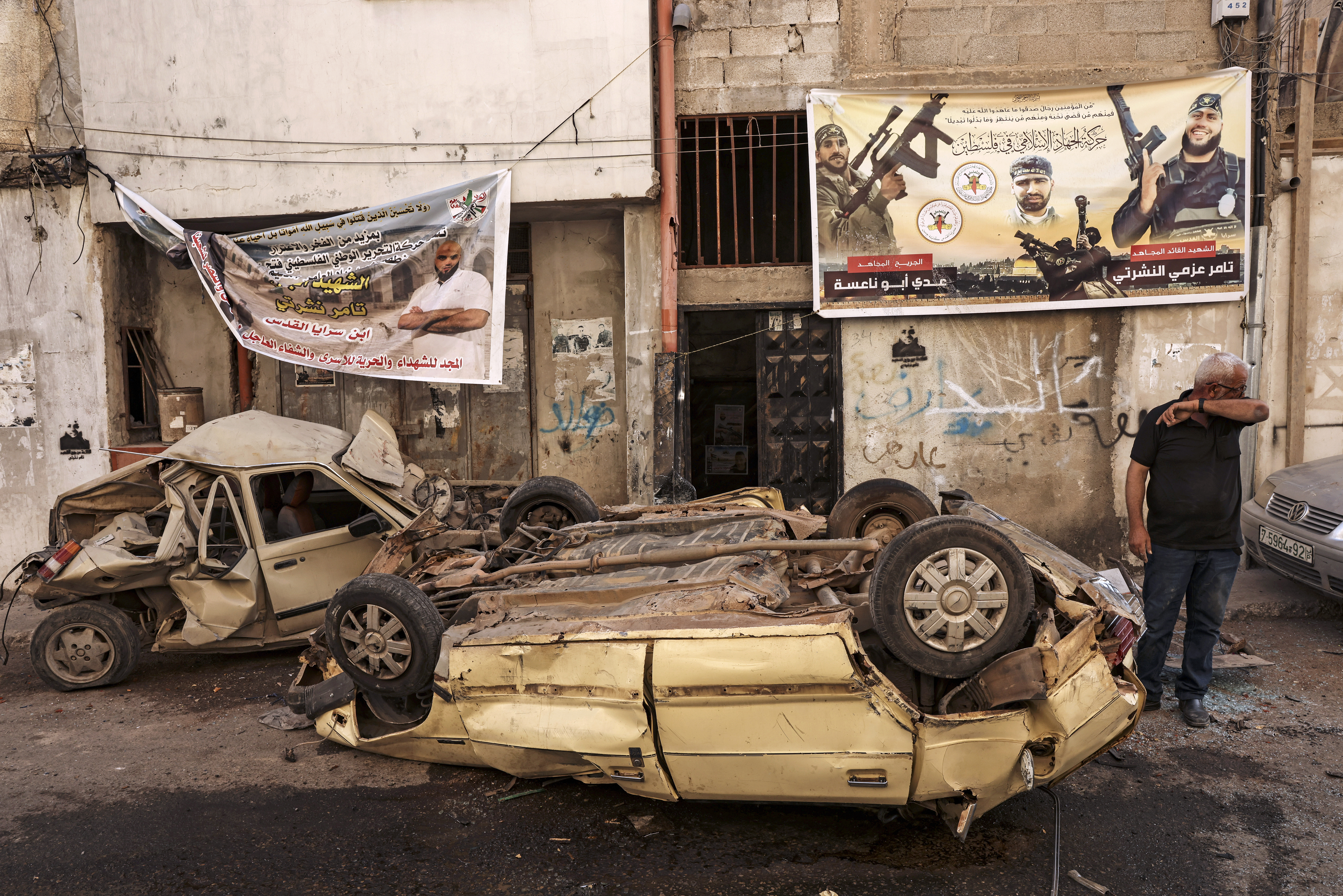 A man stands next to wrecked cars in the aftermath of the Israeli military raid on the Jenin refugee camp in the occupied West Bank