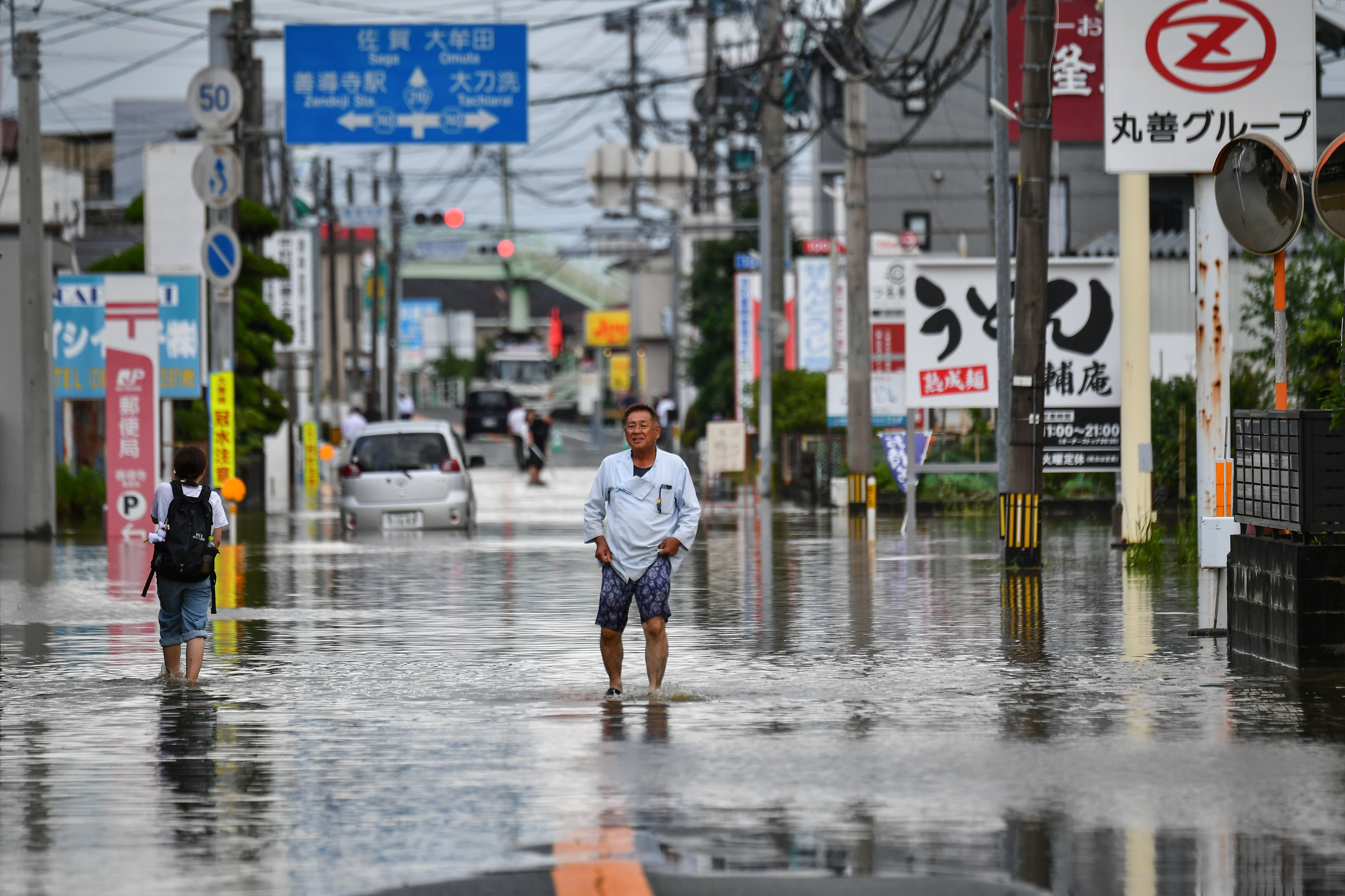 Residents manoeuver through a flooded street in the city of Kureme