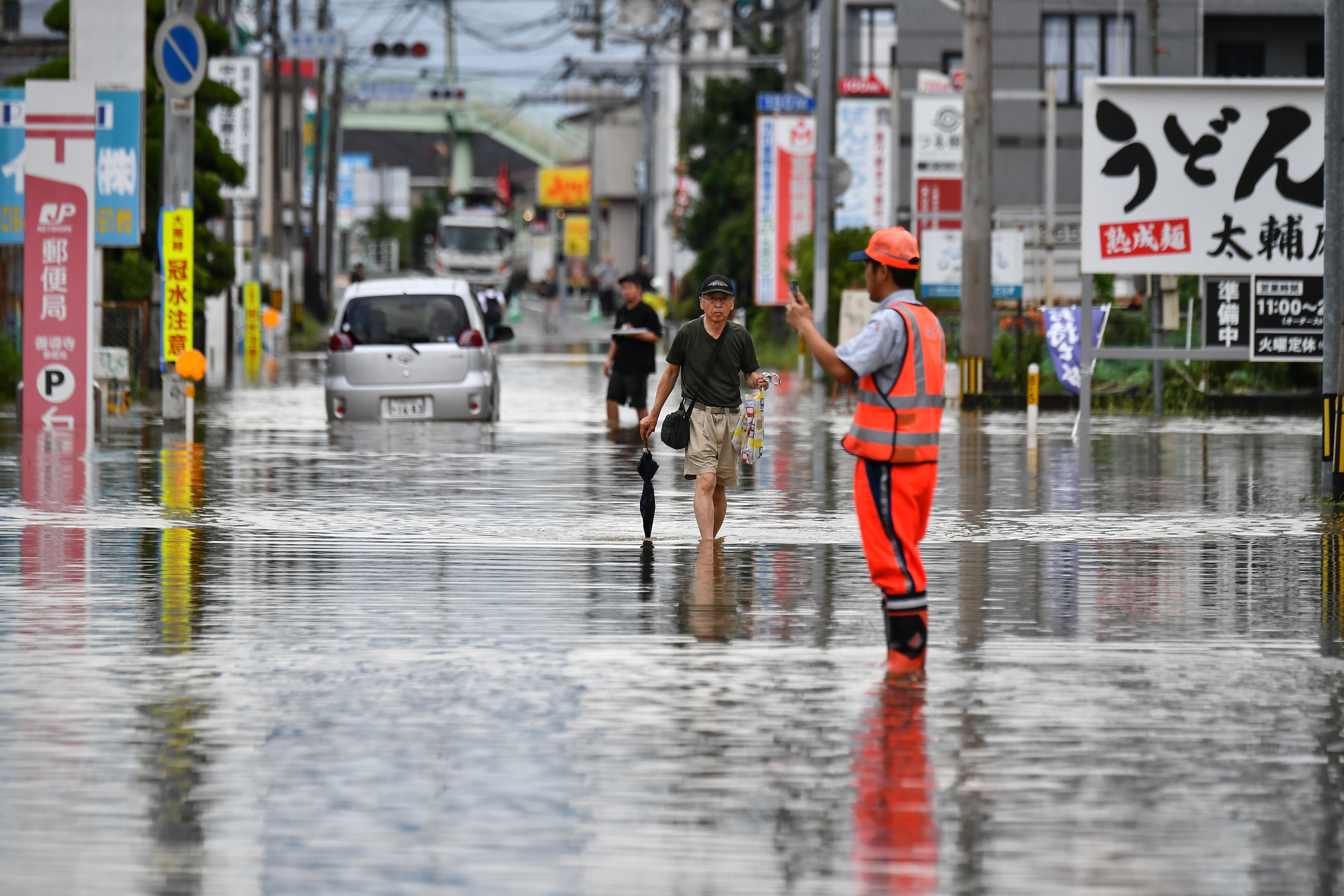 Residents manoeuver through a flooded street in the city of Kureme