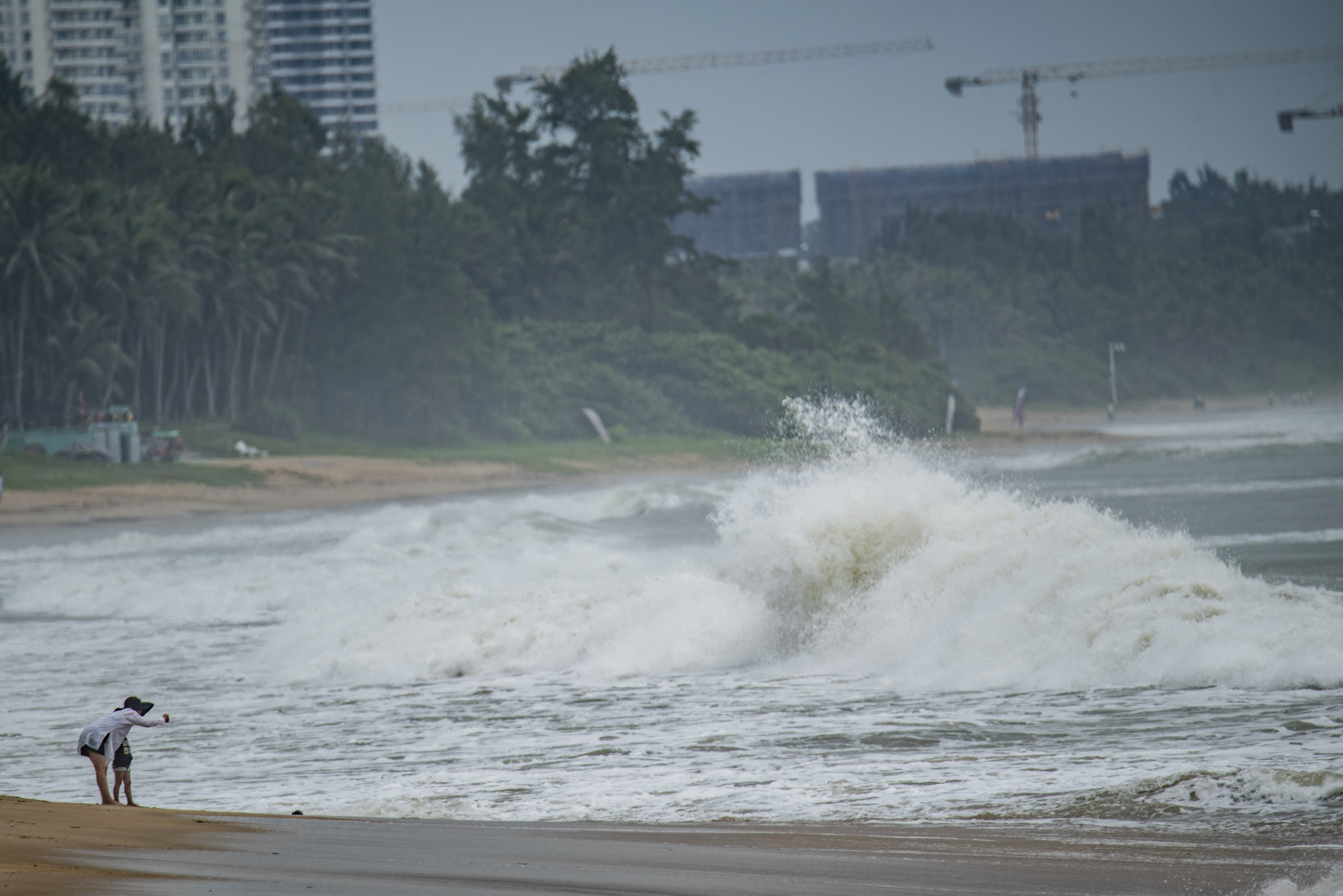 People watch big waves at a sea shore as Typhoon Talim approaches in Boao, in China's southern Hainan province on July 17, 2023.