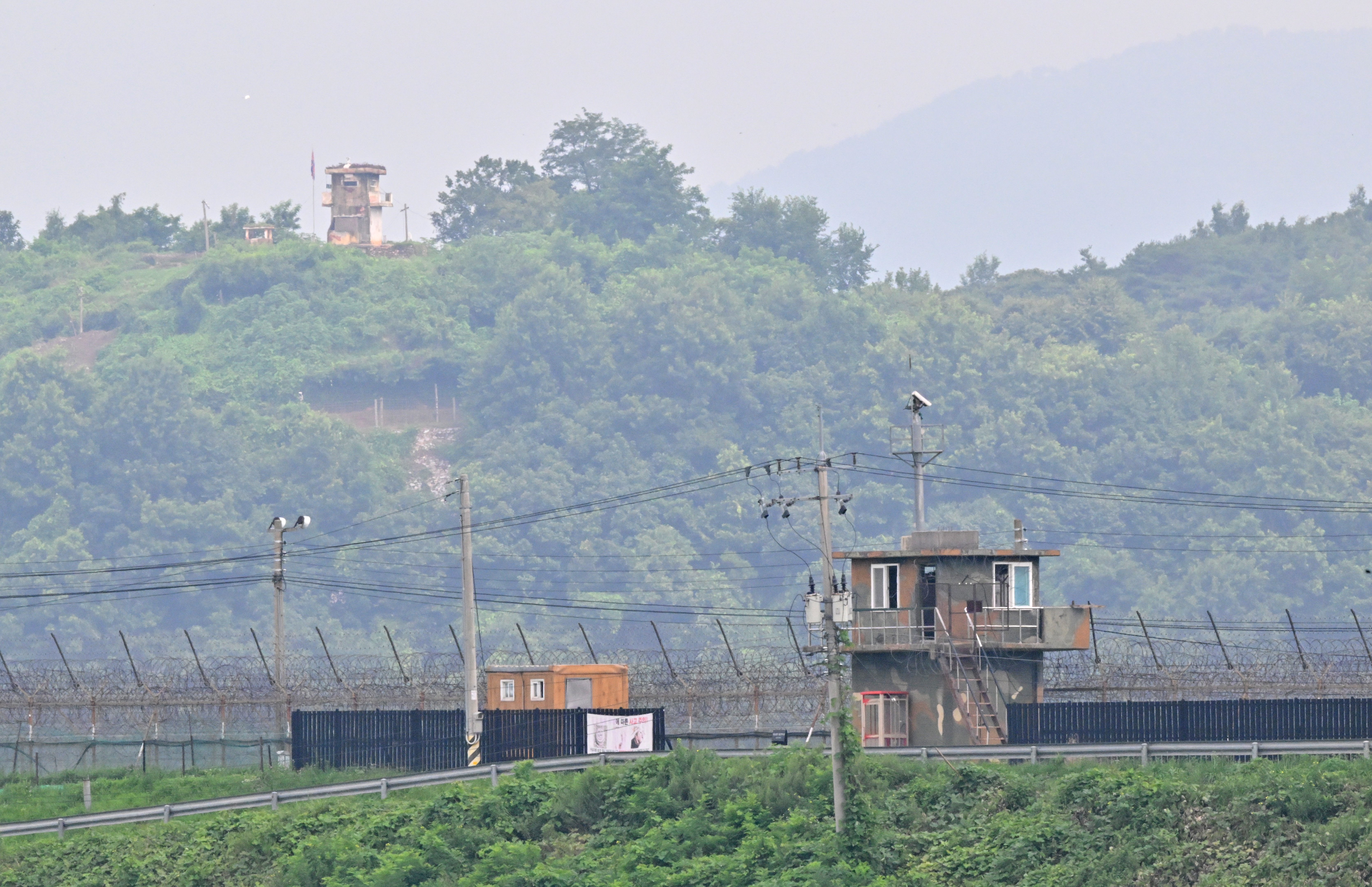 A North Korean guard post (top) on the Korean Demilitarized Zone (DMZ), is seen over a South Korean military fence (bottom) from the border city of Paju on July 19, 2023. - A US soldier who served around two months in a South Korean jail on assault charges was believed to be in North Korean custody on July 19, after crossing the heavily fortified border without authorisation, officials said. (Photo by Jung Yeon-je / AFP)