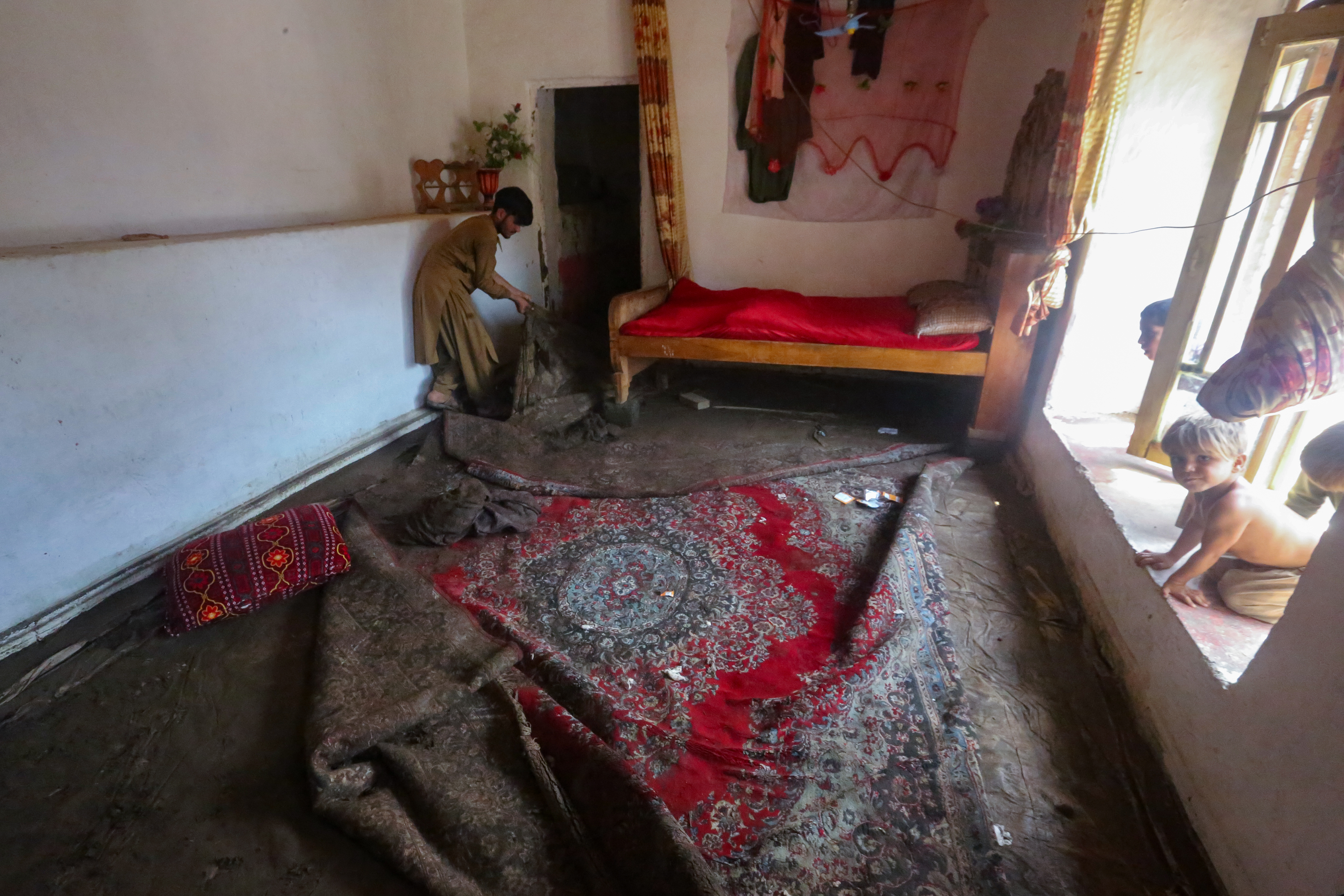 An Afghan resident cleans his house following flash floods in Watapur district of Kunar province