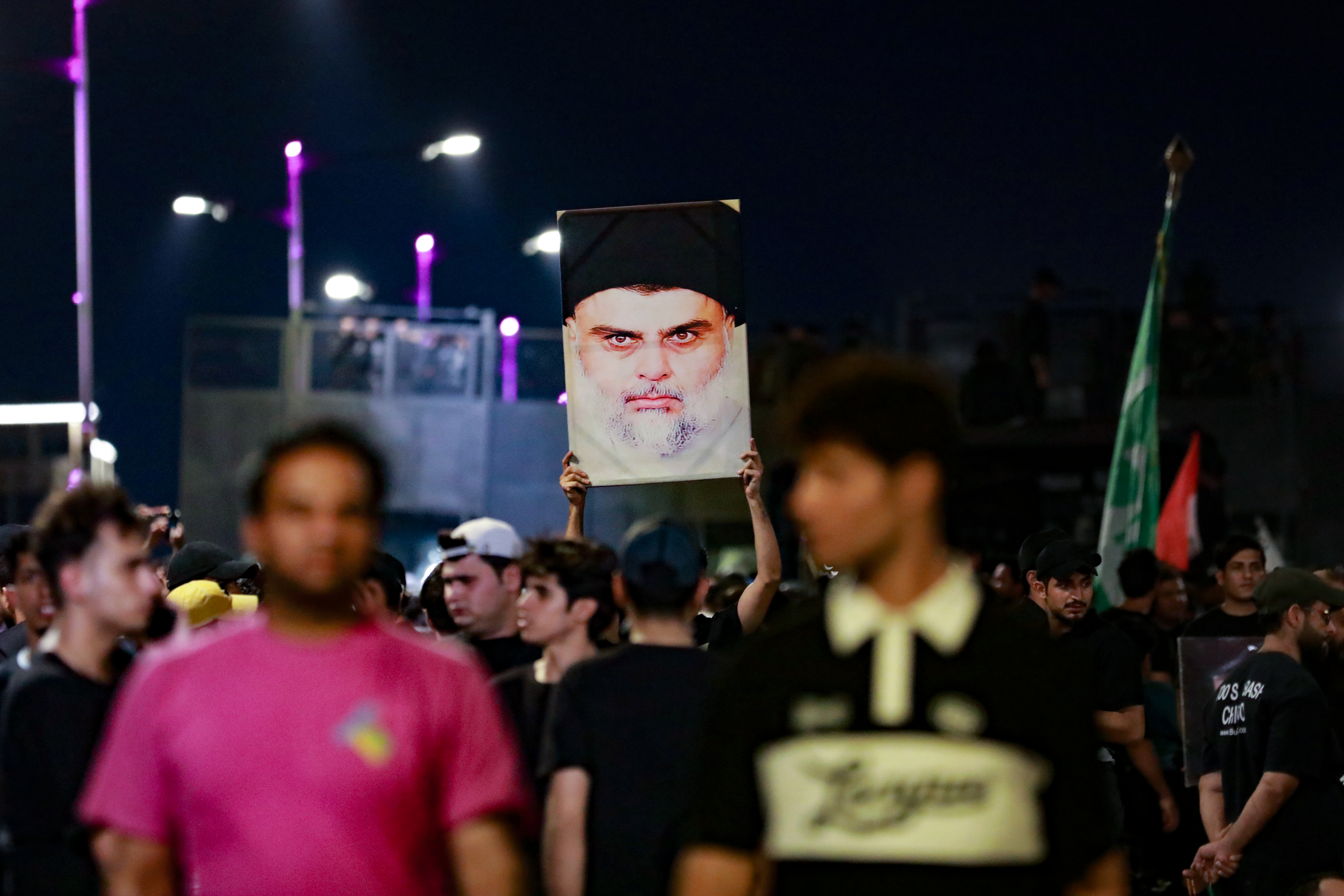 Followers of Iraqi Shiite cleric Moqtada al-Sadr carry his portrait as they protest near Baghdad's Green Zone a day after an alleged burning of the Koran in Copenhagen, early on July 22, 2023. - The protesters were reacting to reports of an apparent desecration of the Muslim holy book in Denmark.