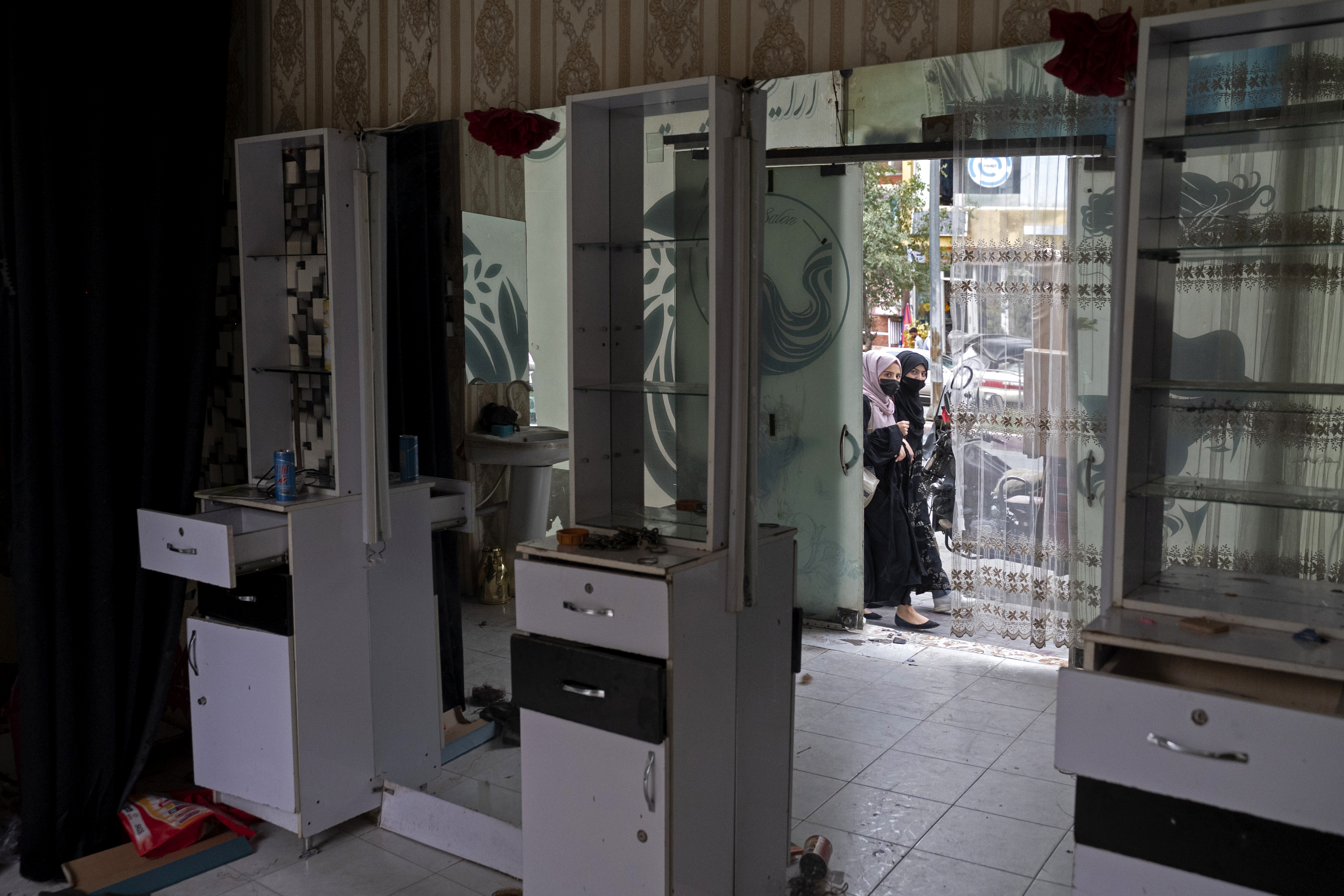 Afghan women peek through the door of a vacated beauty parlour.
