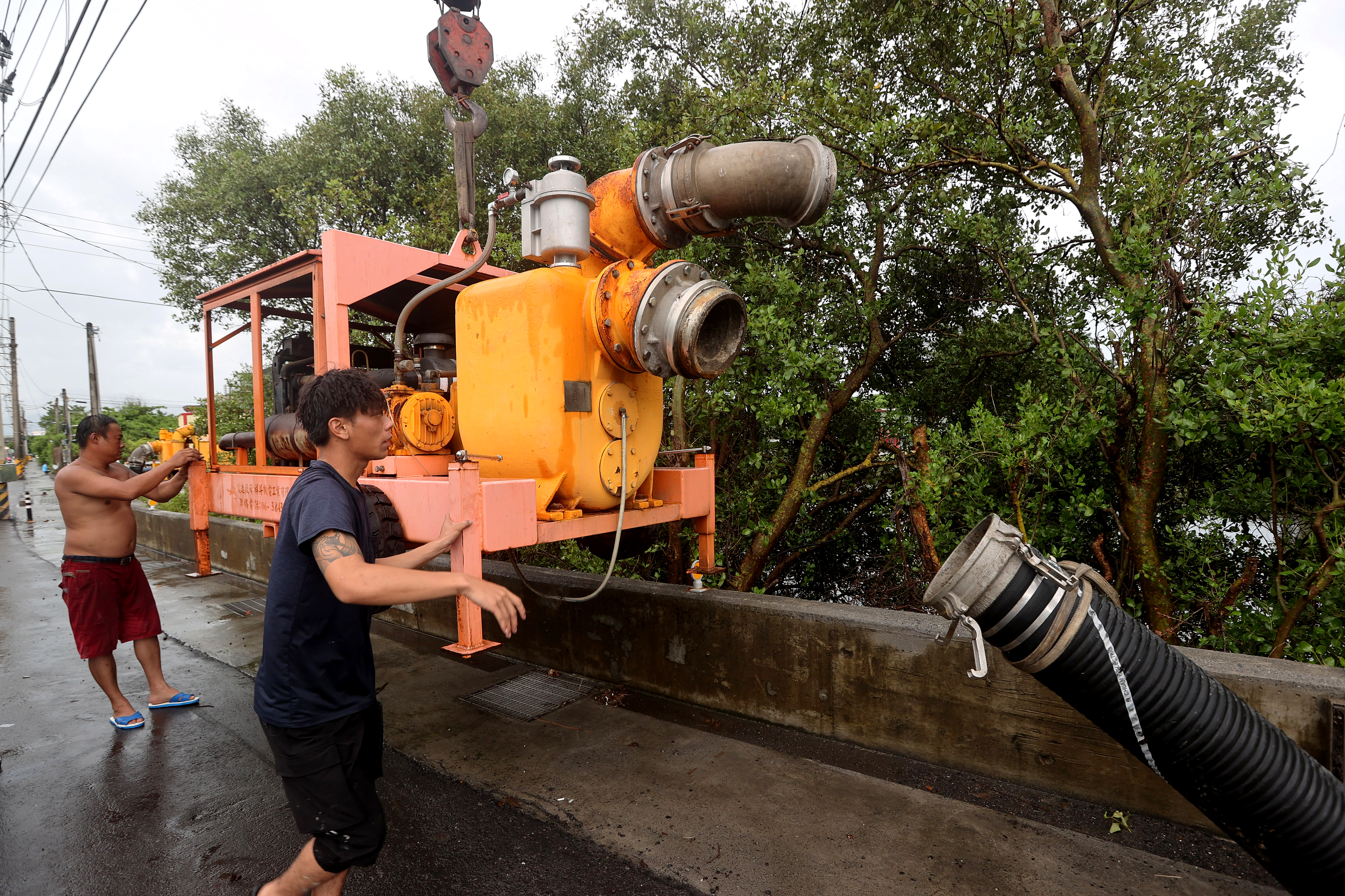 Local residents prepare a water pump in Linbian in western Pingtung County on July 26, 2023, as Typhoon Doksuri past southern Taiwan. - High waves lashed Taiwan's southeastern coast on July 26, with the Central Weather Bureau issuing warnings and heavy rain advisories. (Photo by Johnson LIU / AFP)