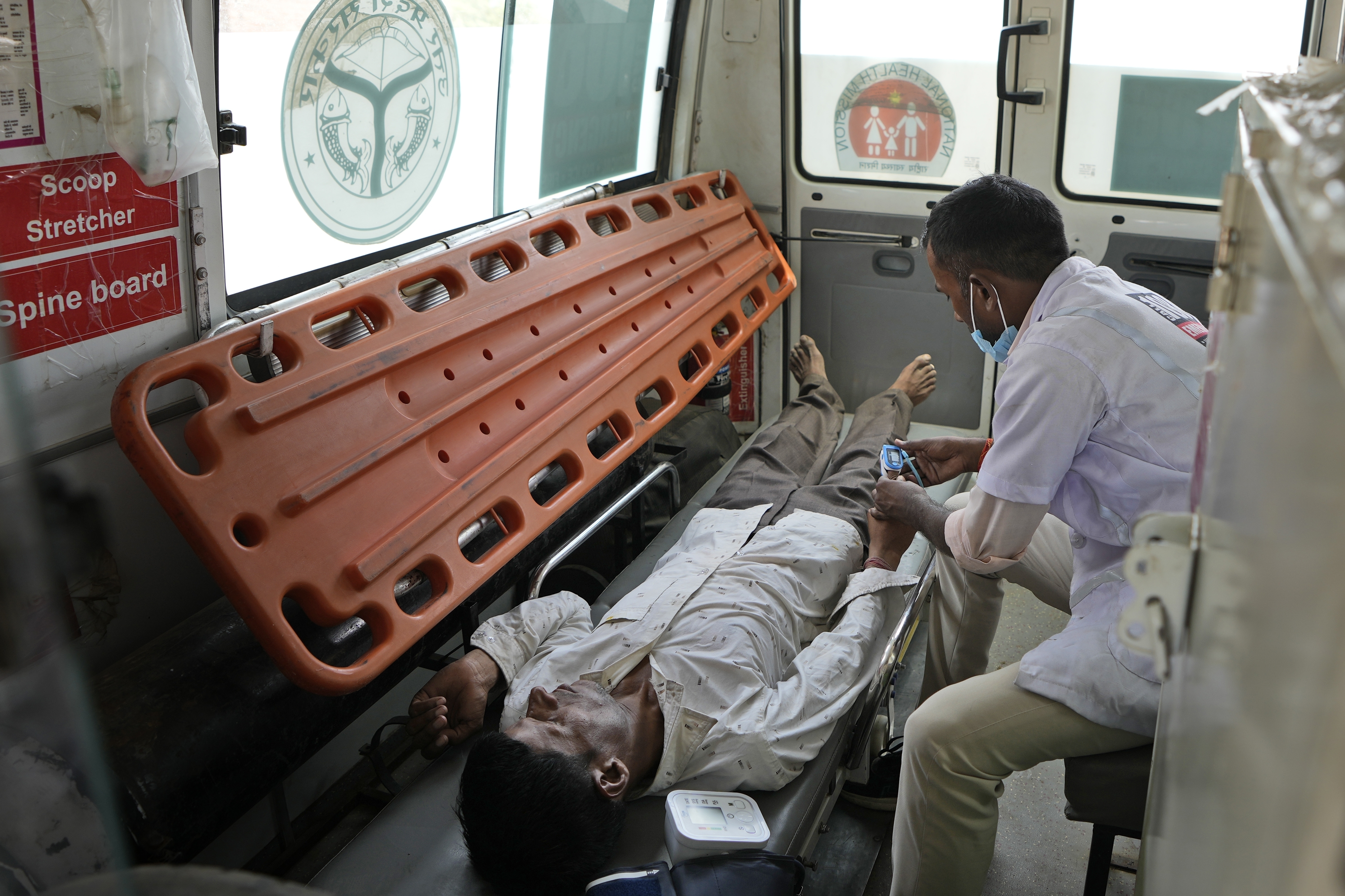 Jitendra Kumar, a paramedic checks the oxygen level of his patient who is suffering from a heat stroke after carrying him in an ambulance from his home in village Mirchwara, 24 kilometers (14.91 miles) from Banpur in Indian state of Uttar Pradesh, Saturday, June 17, 2023
