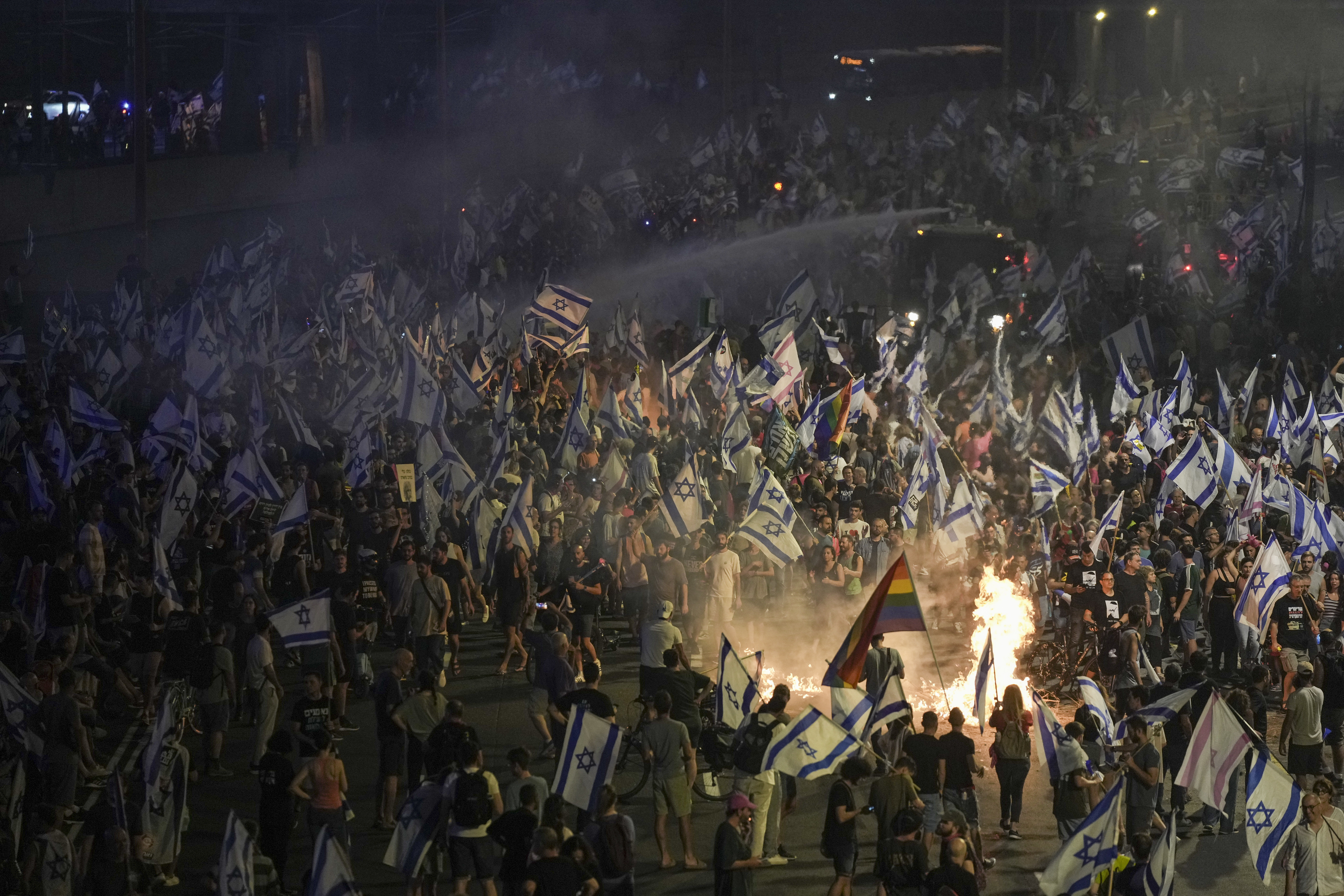 Israeli police use a water cannon to disperse demonstrators blocking the freeway during protest against plans by Prime Minister Benjamin Netanyahu's government to overhaul the judicial system in Tel Aviv, Israel, Wednesday,
