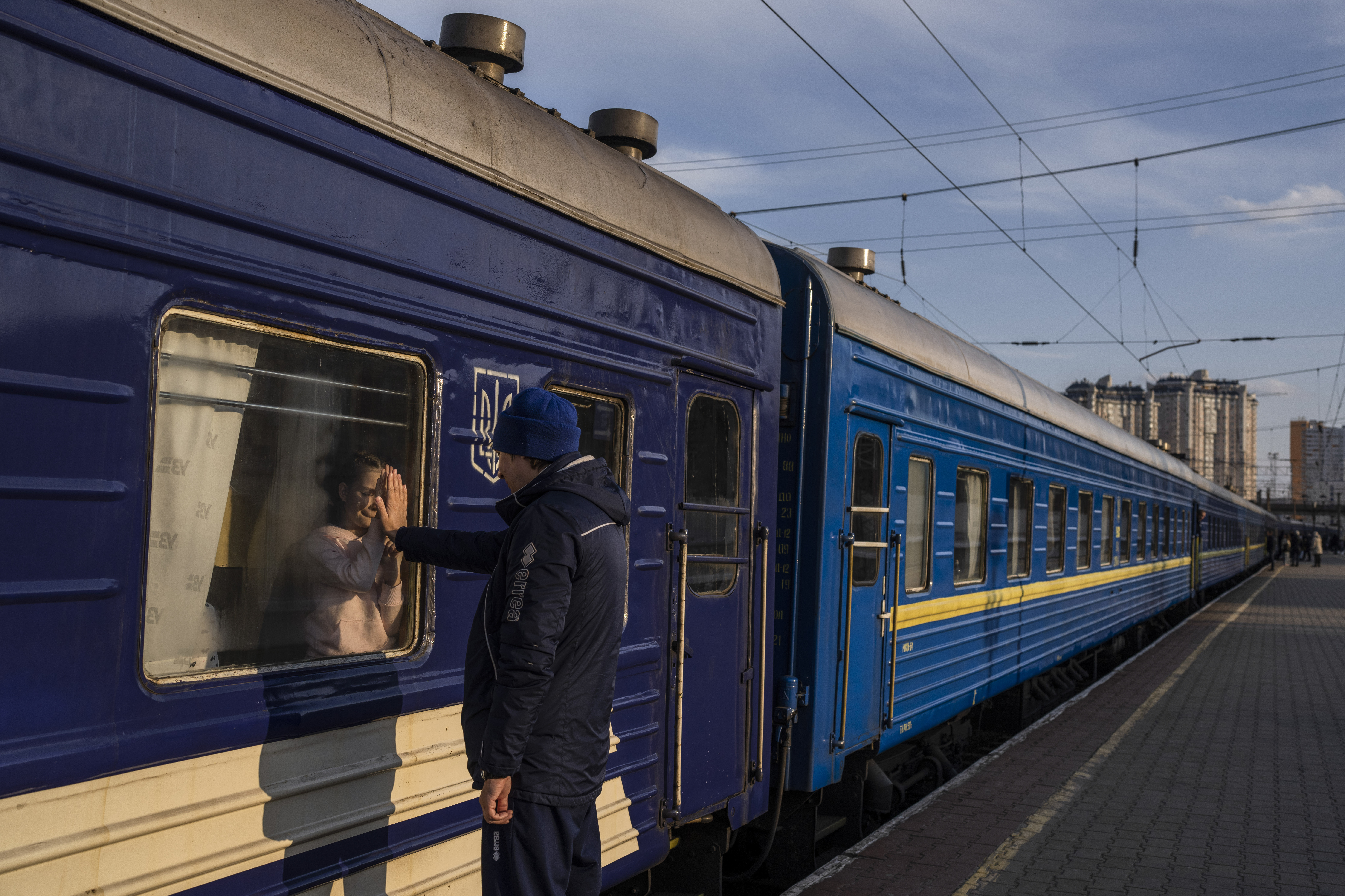 Ruslan Mishanin, 36, right, bids farewell to his nine year old daughter as the train with his family leaving for Poland, at the train station in Odesa,