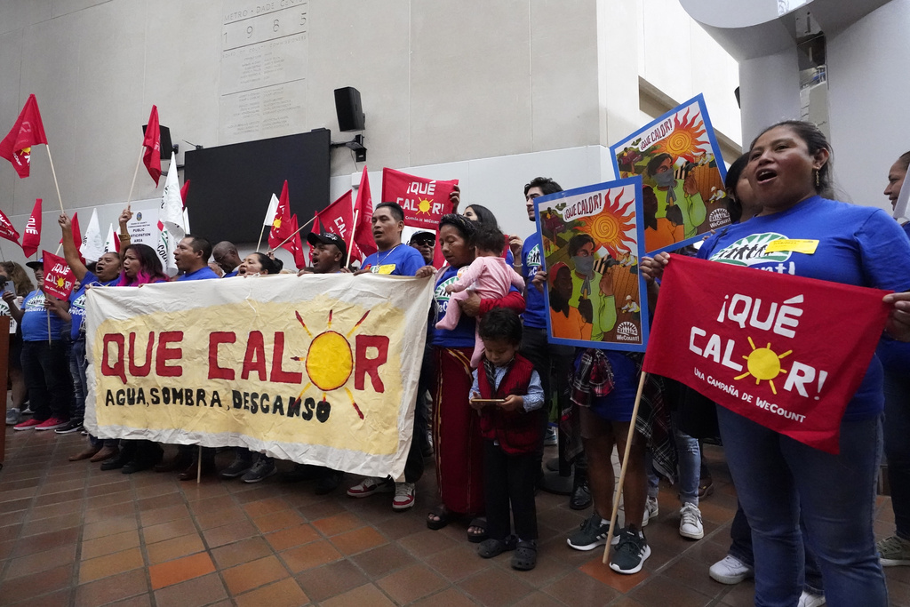 Workers hold signs calling for protections against extreme heat