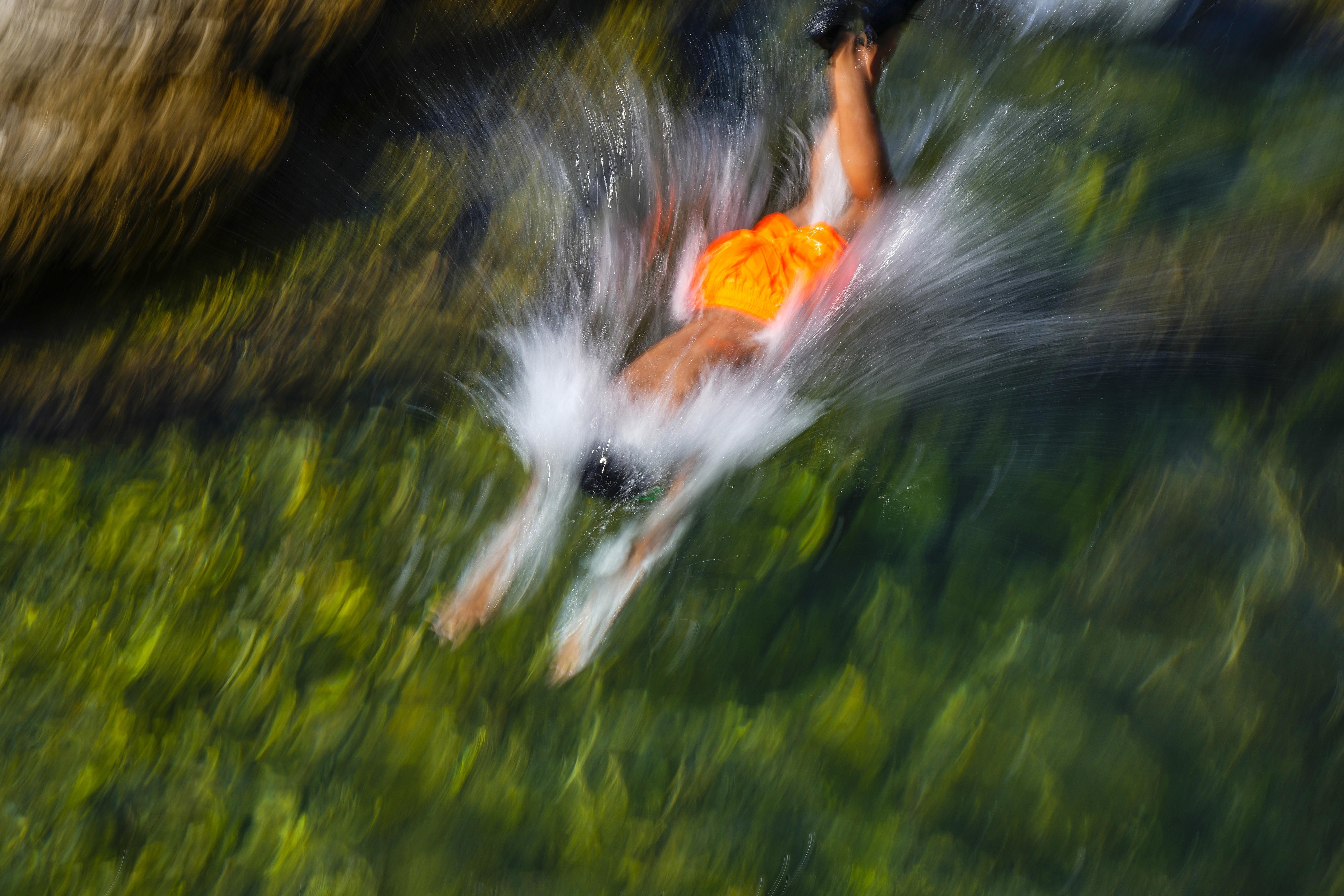 A young man jumps in the water to cool off on a sweltering day in the Mediterranean Sea