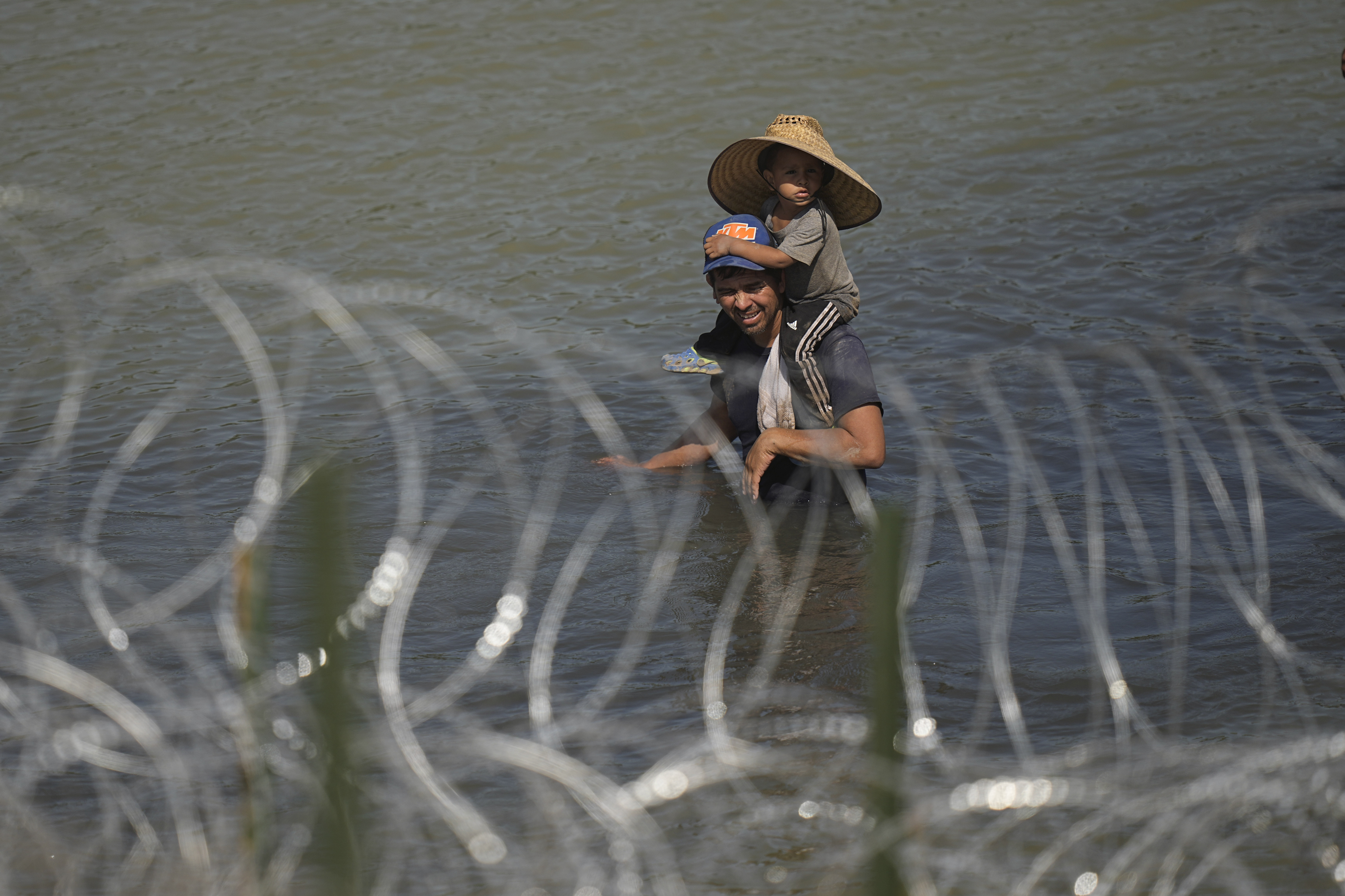 Migrants, one a child, stand in the Rio Grande