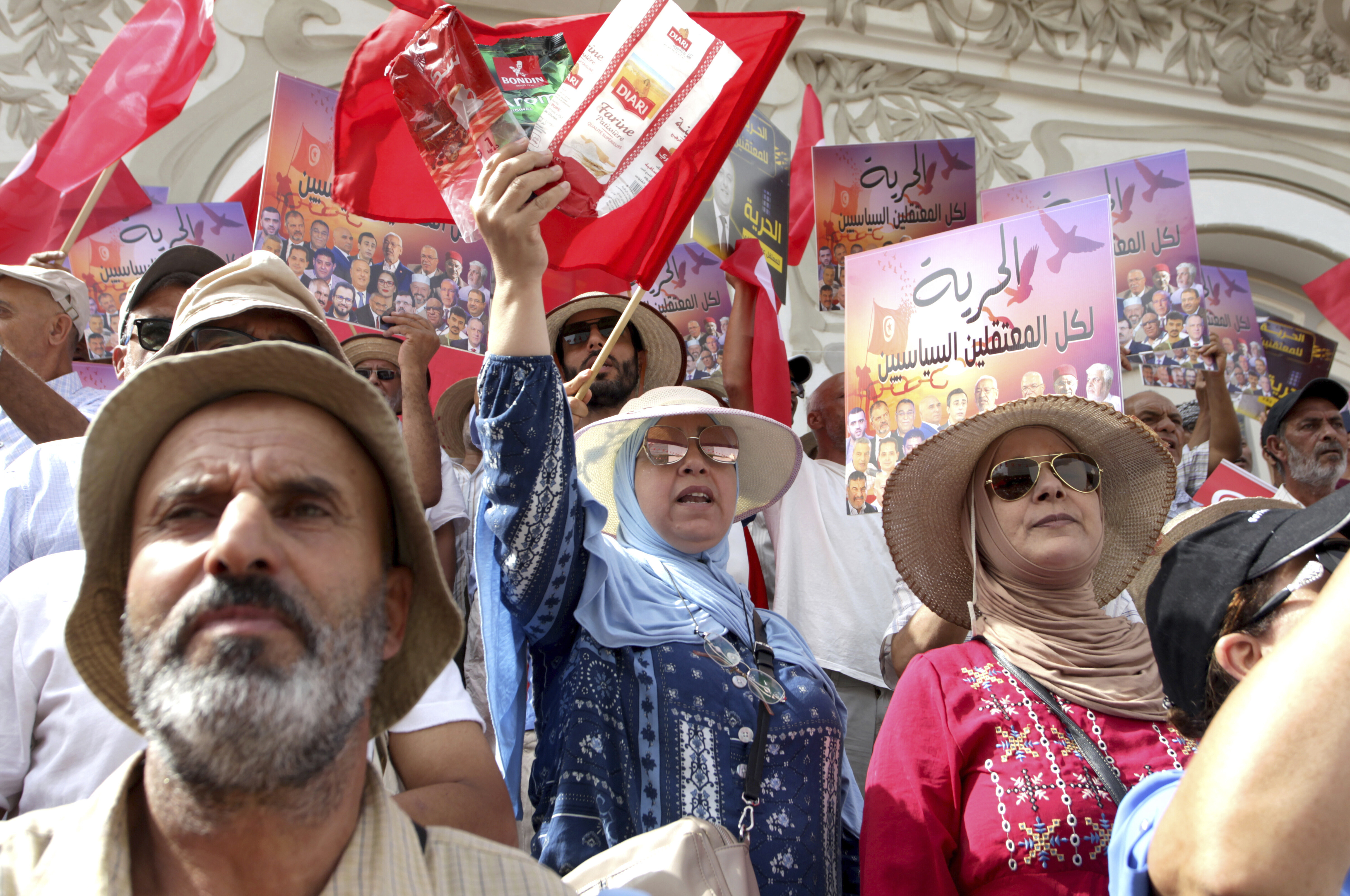 Tunisians demonstrate against Tunisian President Kais Saied during the Tunisian Republic Day in Tunis, Tunisia, Tuesday, July 25, 2023. The sign reads in Arabic: "Freedom for all political prisoners". (AP Photo/Hassene Dridi)