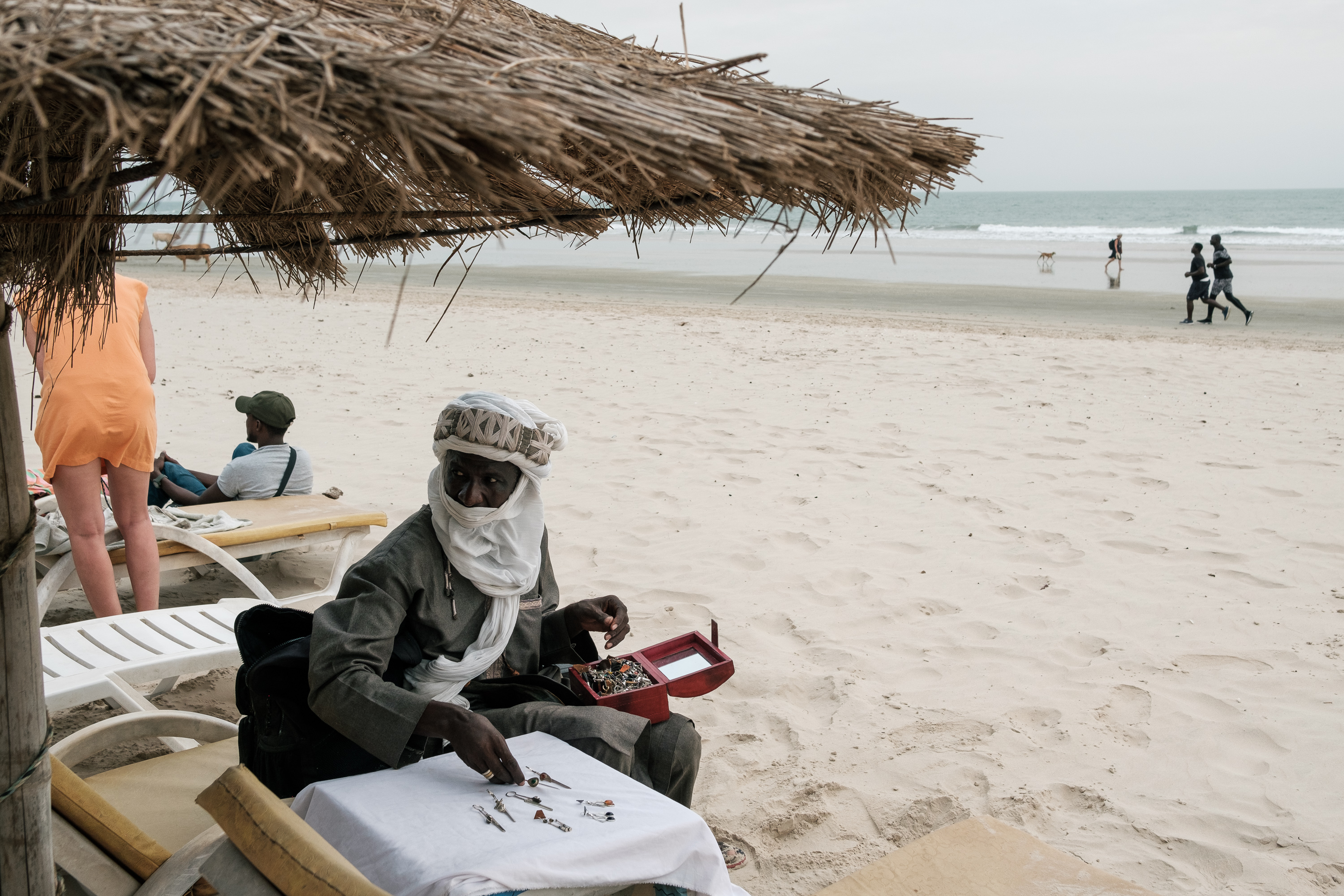 Almounzer Dicko sets up a display table taking jewelry out of boxes and bags he carries around in Cap Skirring in Casamance carrying his jewelry in bags and boxes from Mali approaching tourists on the beach to buy his products