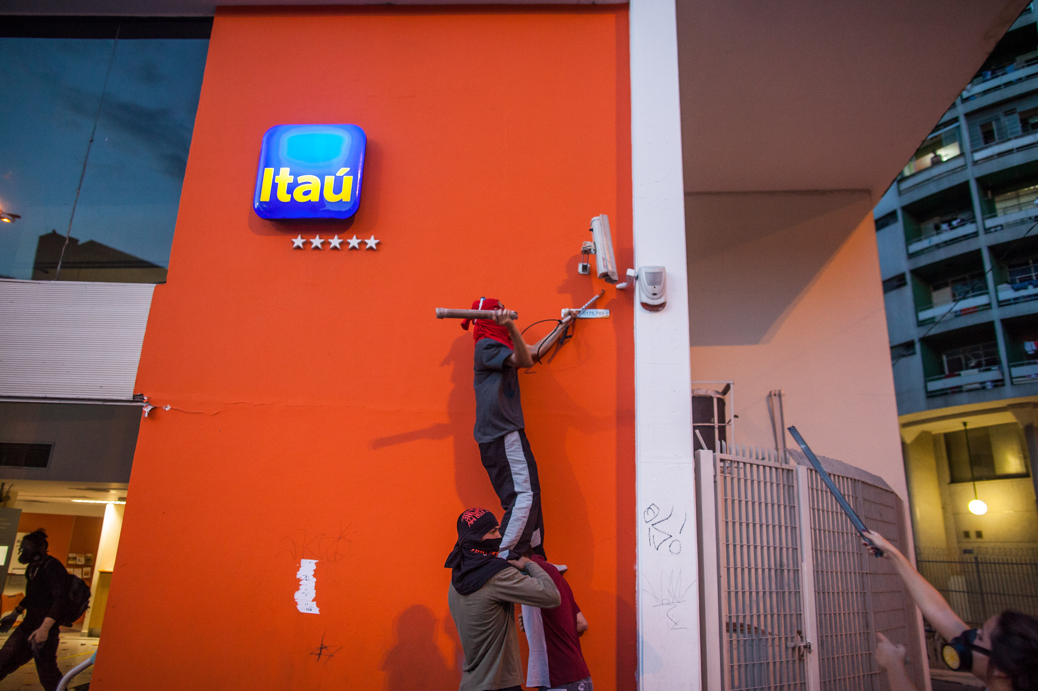 A protester n Sao Paulo, Brazil smashes a banks security camera during demonstrations against the staging of the upcoming 2014 World Cup