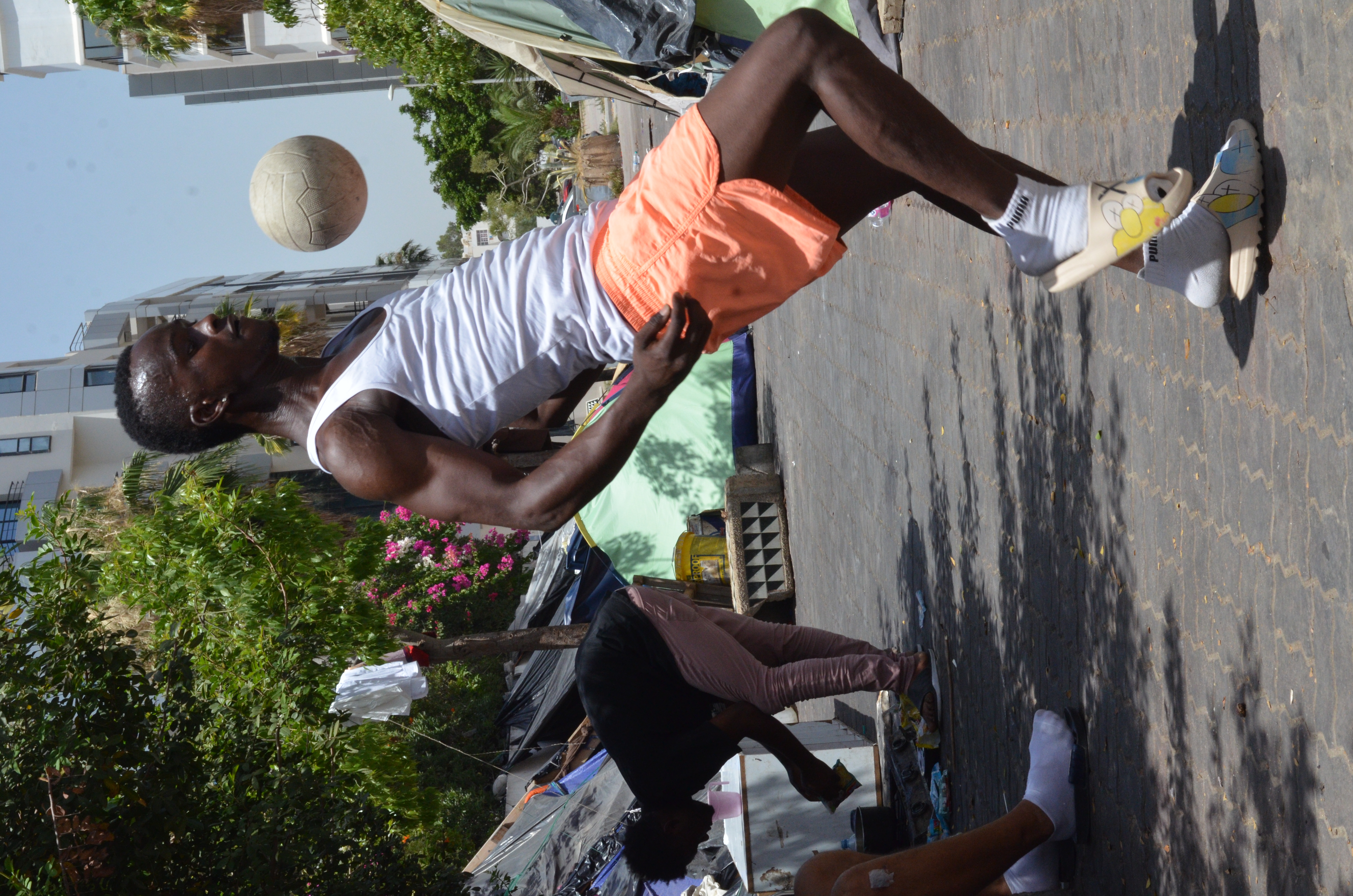 Ignoring the heat, Jalel, from Guinea, formerly a professional footballer, practices his skills with a child's ball. His ambition is to play for a club in Europe.