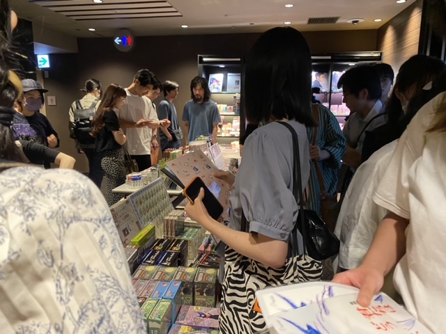 Japanese fans queuing for tickets to see Hayao Miyazaki's latest film. There are inside the cinema. They have booklets with the poster for the fiilm.