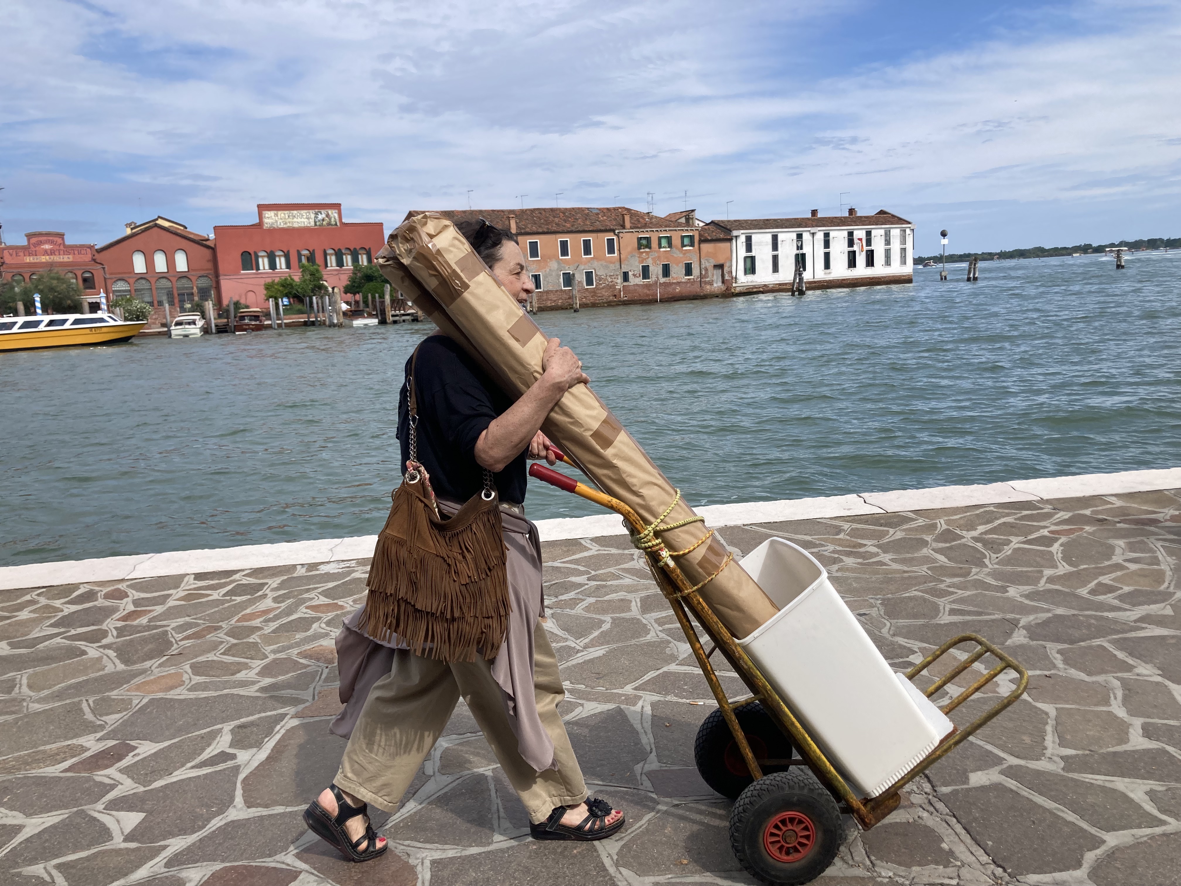 A glassblower walks with her purchases in Murano
