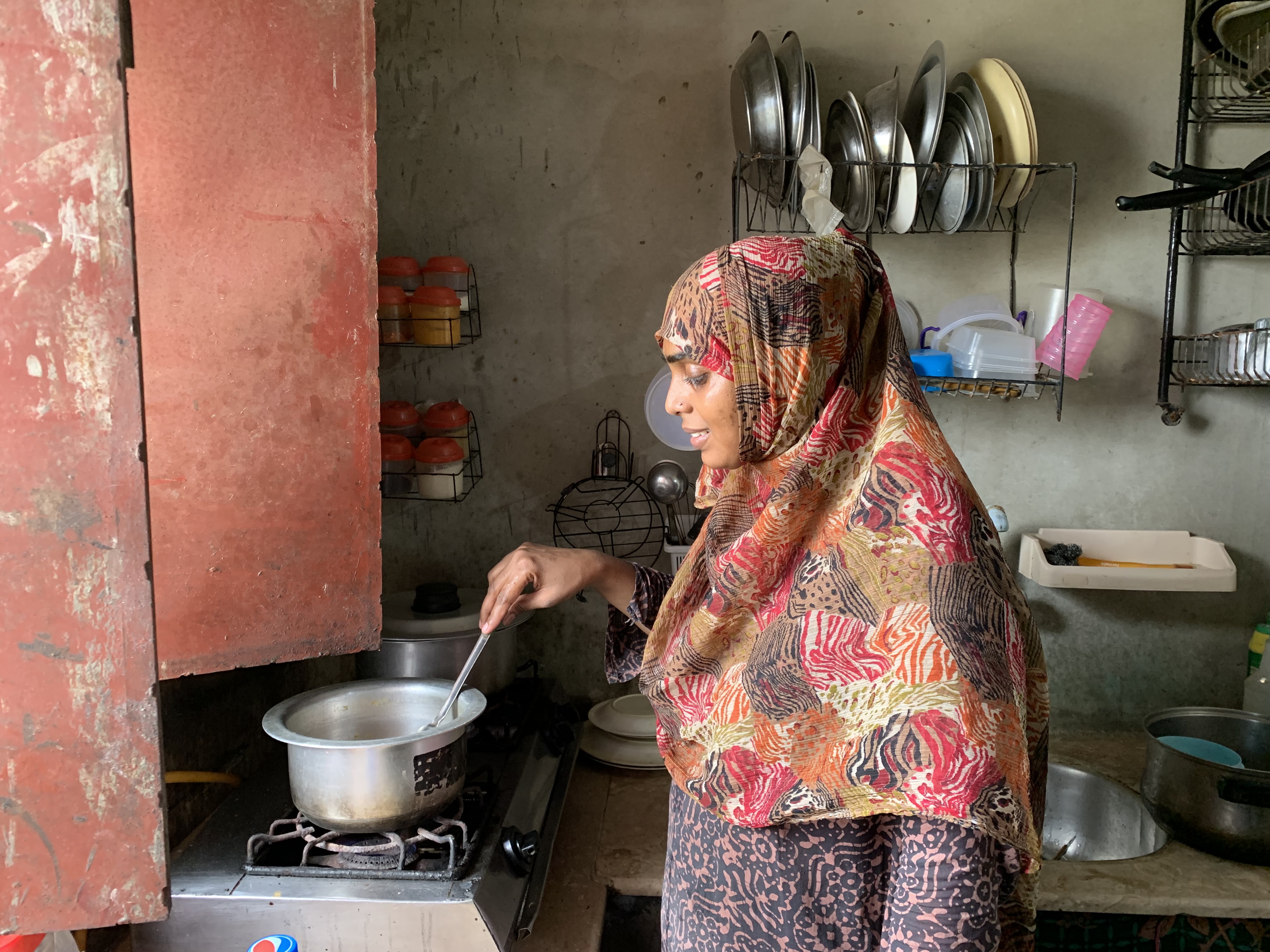 A photo of Aisha cooking dinner in her kitchen.