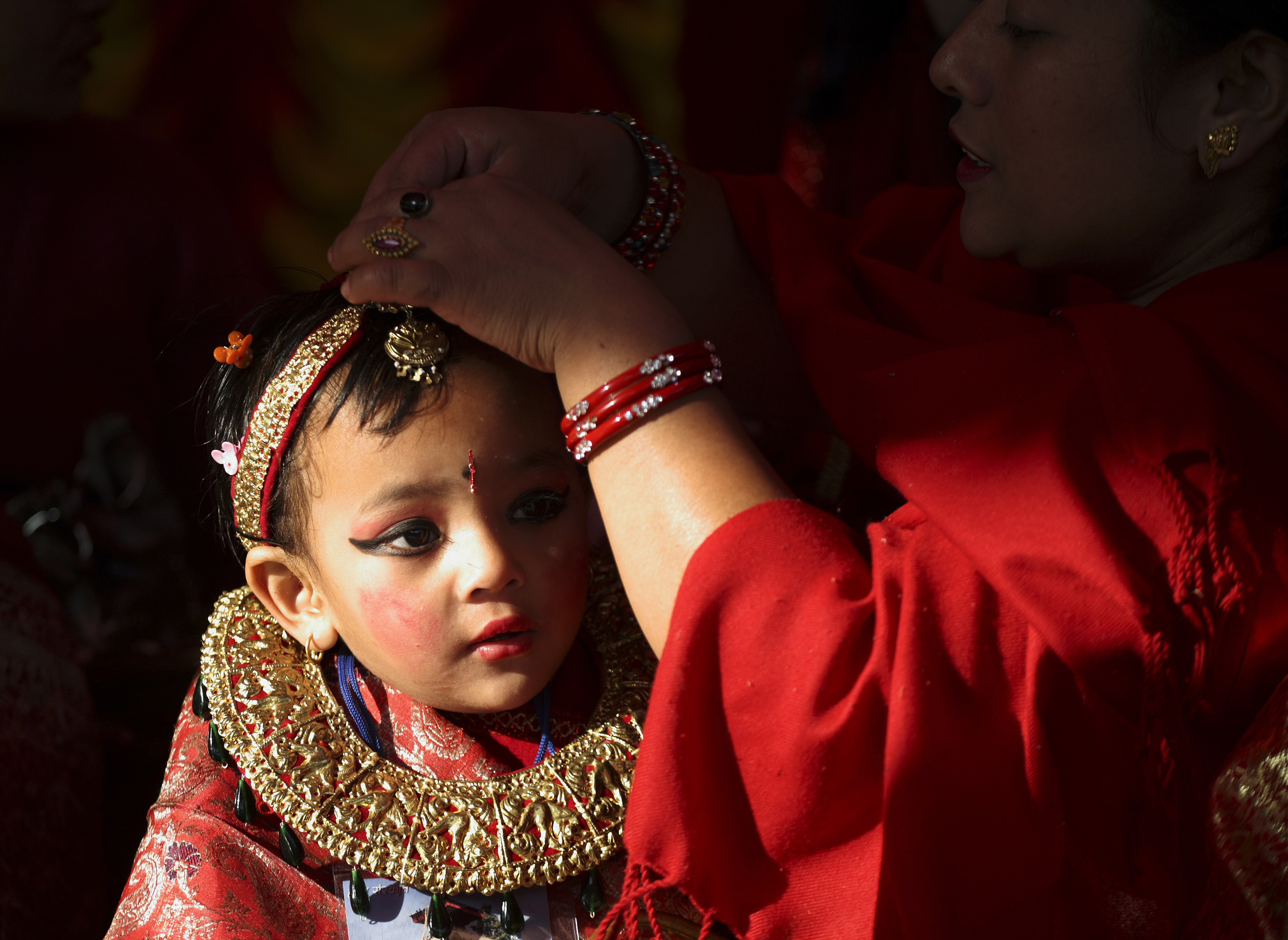 A Newar girl gets the final touches from her mother before the Ihi rituals of her first marriage ceremony in Kathmandu November 21, 2009. Girls aged odd years before puberty are married to Bel, the fruit of an wood-apple tree in the ceremony. Ihi is a two-day ceremony which begins with purification rituals and ends with "Kanyadan" (giving away the virgin) of the girl by her father. In this way, a Newar girl is married thrice in her life first with a wood apple tree fruit. A second time with the sun and finally with a human later in life. REUTERS/Shruti Shrestha (NEPAL SOCIETY RELIGION)