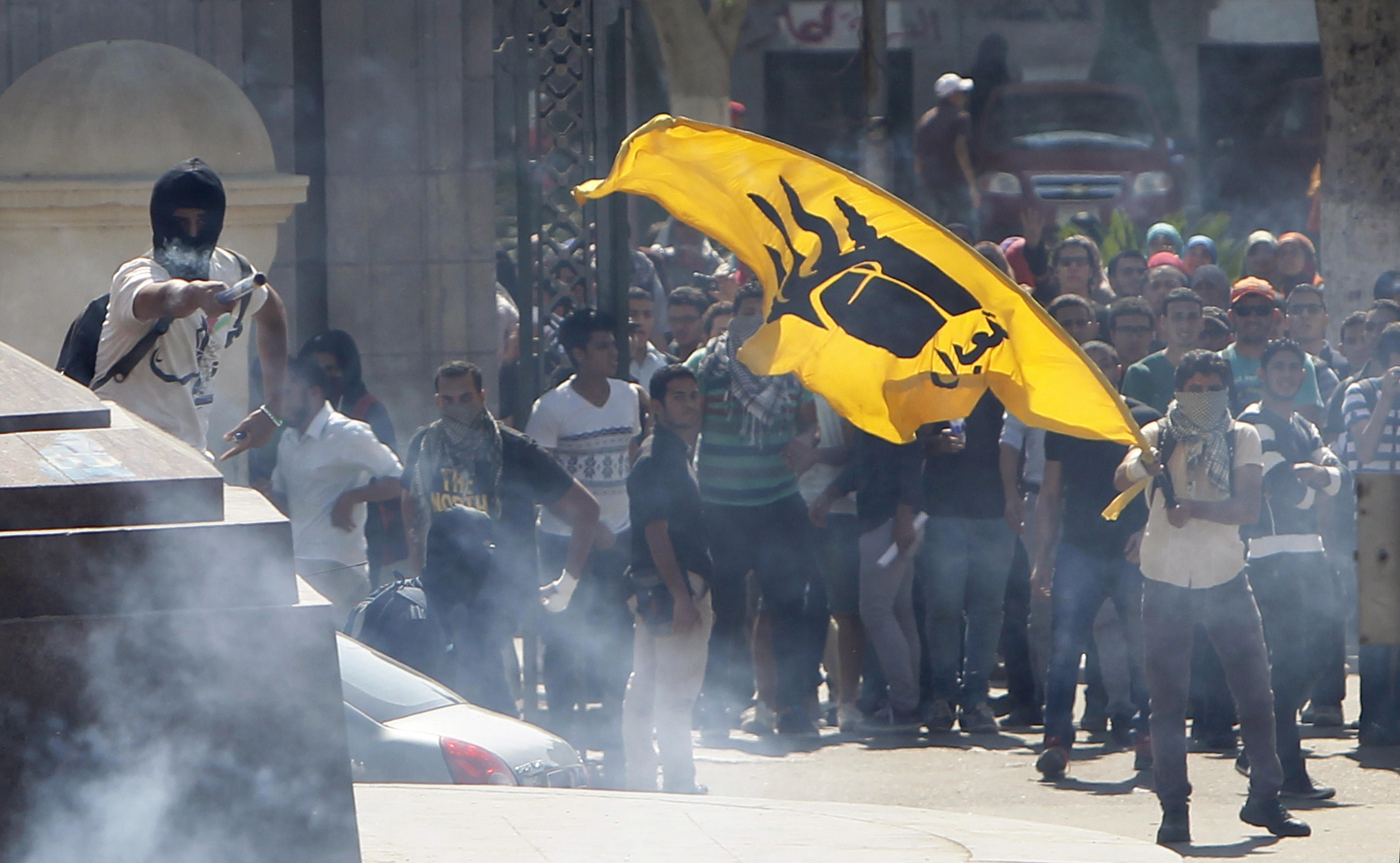 A student supporter of the Muslim Brotherhood and ousted President Mohamed Mursi holds a yellow flag bearing the four-fingered Rabaa sign