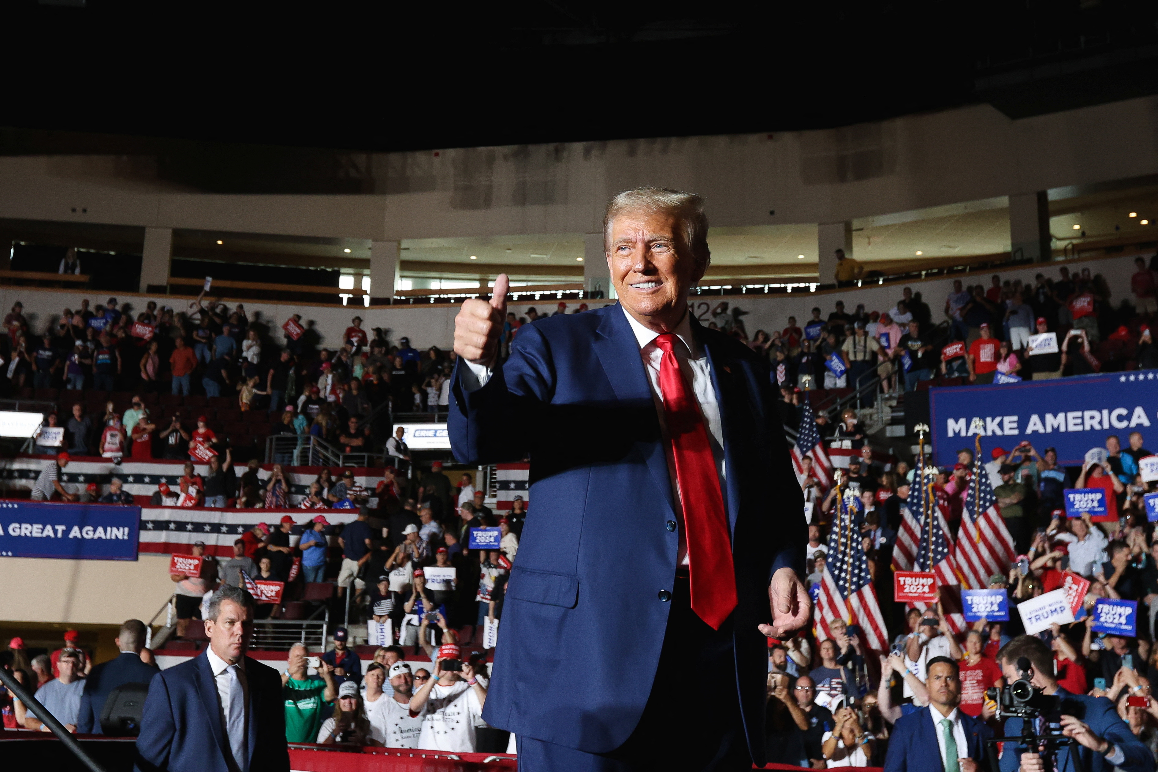 The former president, surrounded by an auditorium of supporters, flashes a thumbs-up.