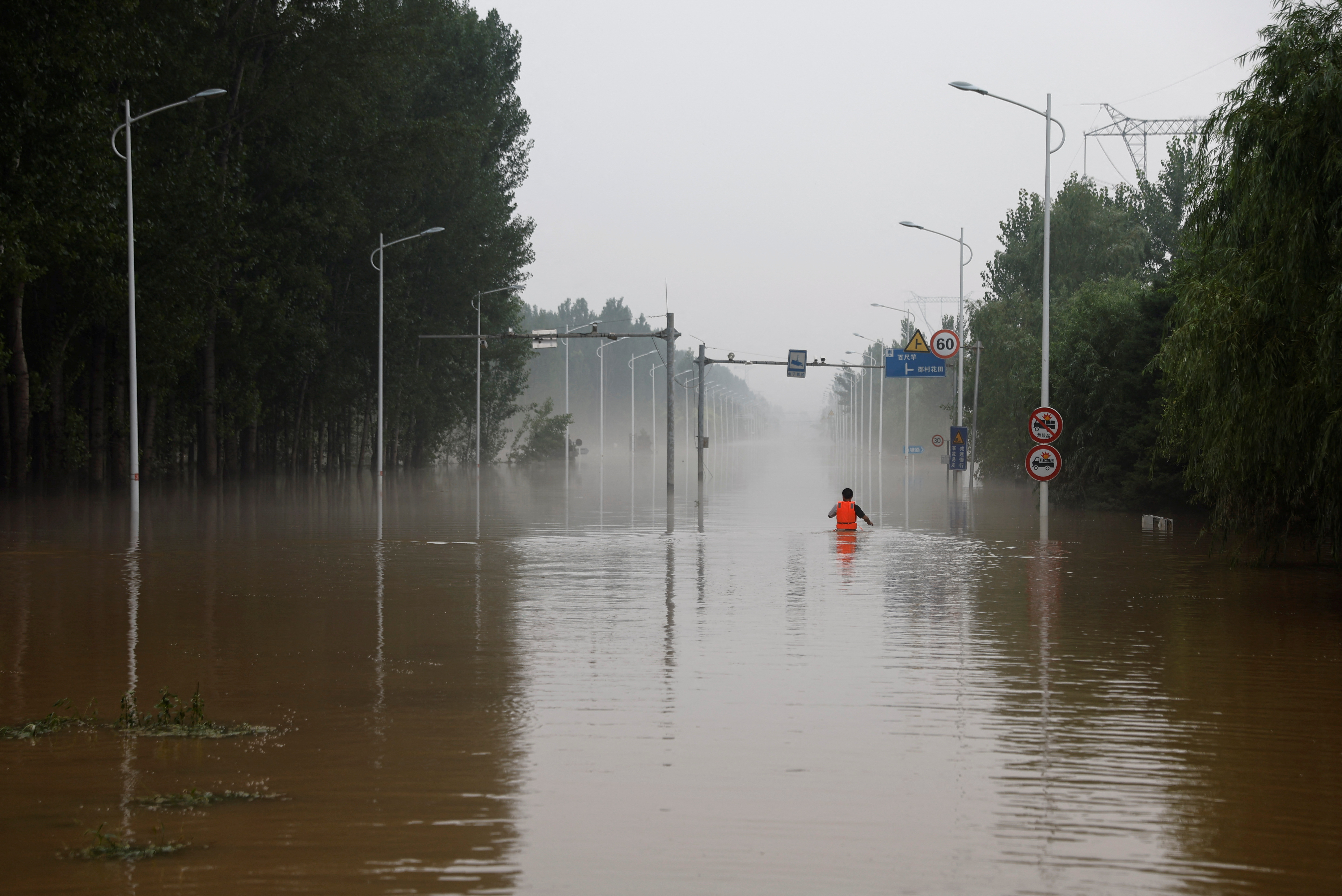 A man makes his way through a flooded road after the rains and floods brought by remnants of Typhoon Doksuri