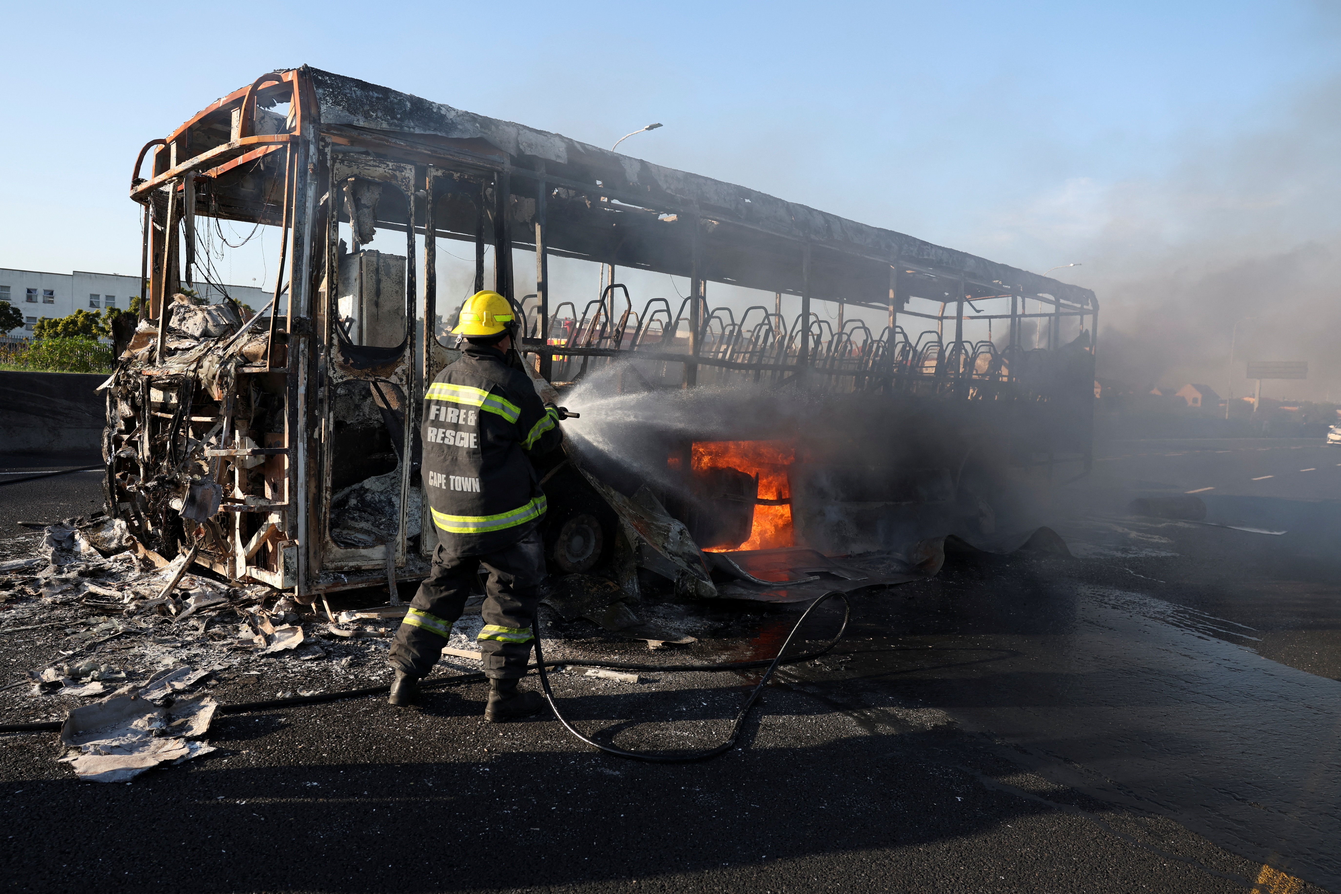 Firemen extinguish a burning bus which was set alight during a protest by taxi operators over a number of grievances against traffic authorities in Cape Town, South Africa, August 3, 2023. REUTERS/Esa Alexander