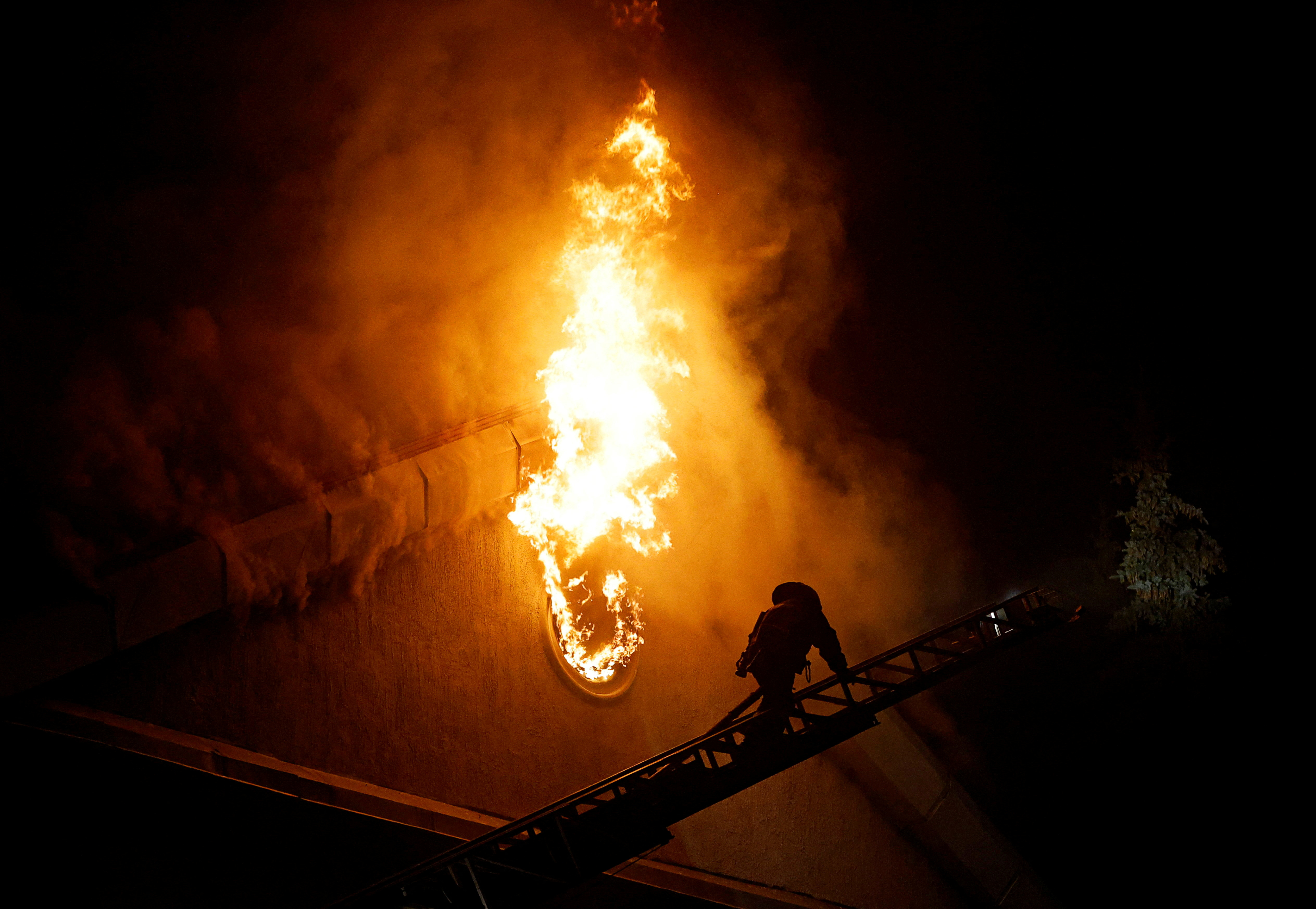 A firefighter climbs a ladder while extinguishing a fire in the university building following a reported shelling in the course of Russia-Ukraine conflict in Donetsk, Russian-controlled Ukraine.