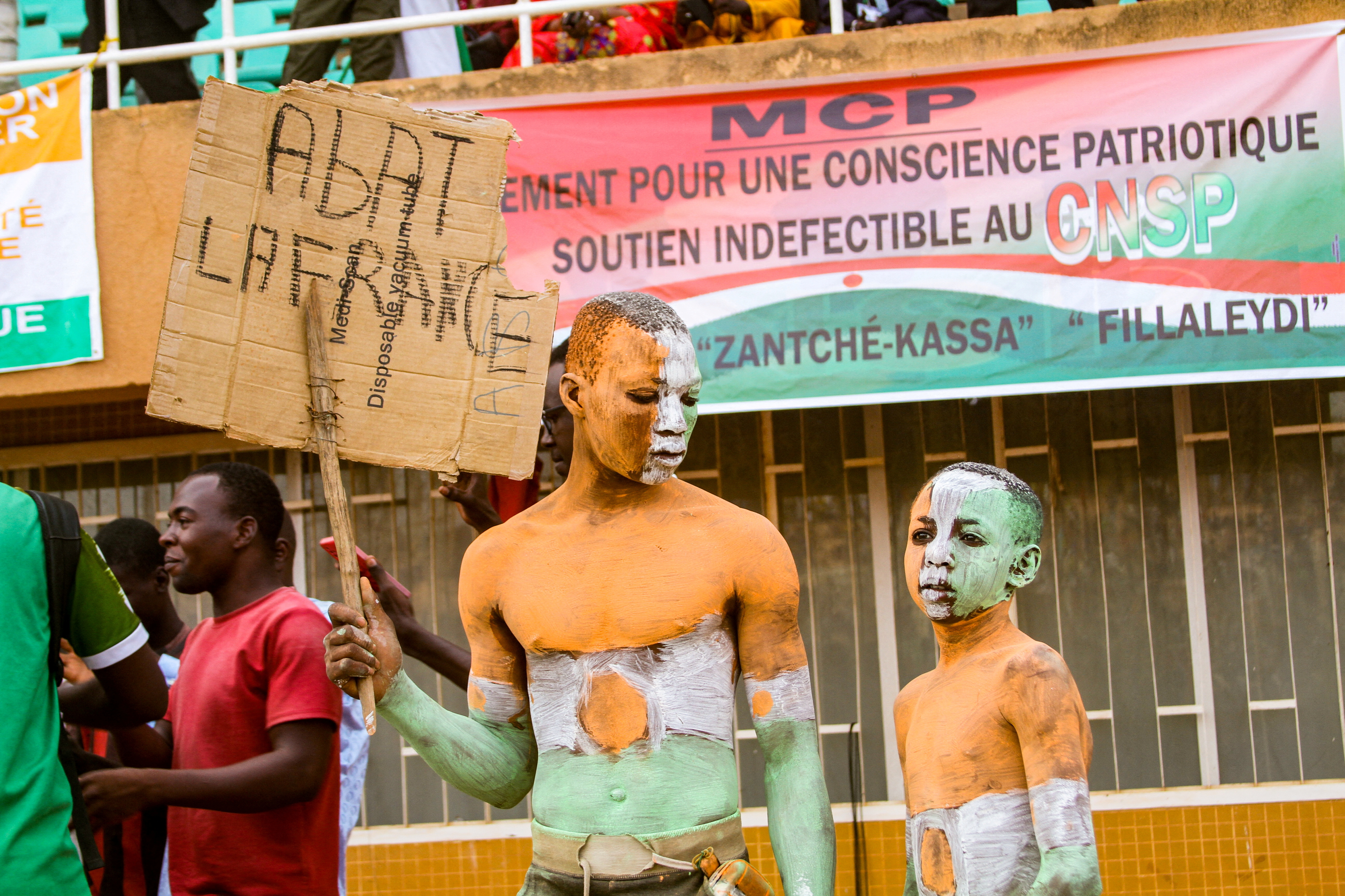 A supporter of Niger's coup leaders holds a sign reading "Knock down France" in Niamey
