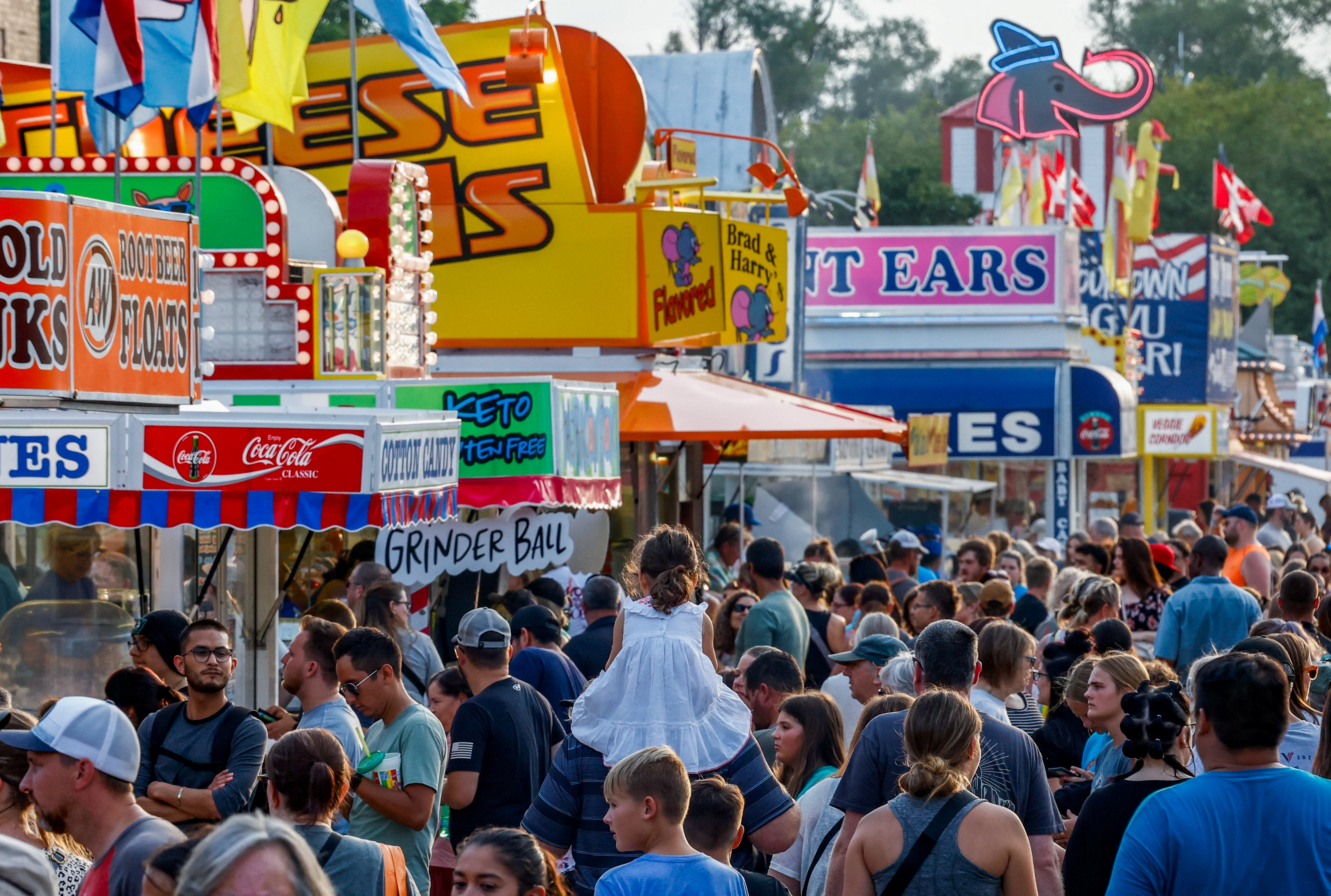 A view over the top of the crowds at the Iowa State Fair, as visitors filter past stalls for food and games.