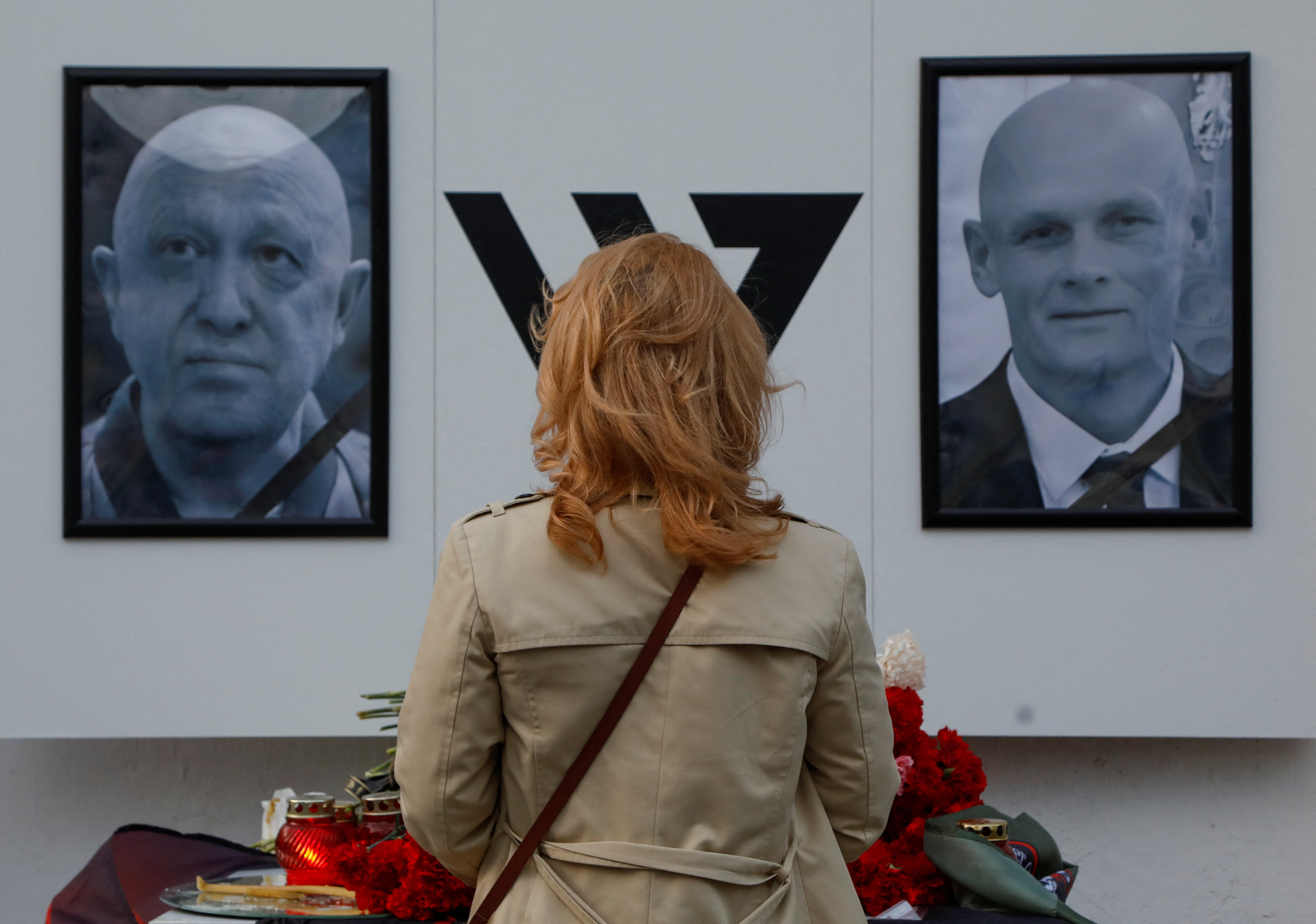 A woman stays in front of a makeshift memorial for Yevgeny Prigozhin, head of the Wagner mercenary group, and Dmitry Utkin, group commander, in Nizhny Novgorod, Russia