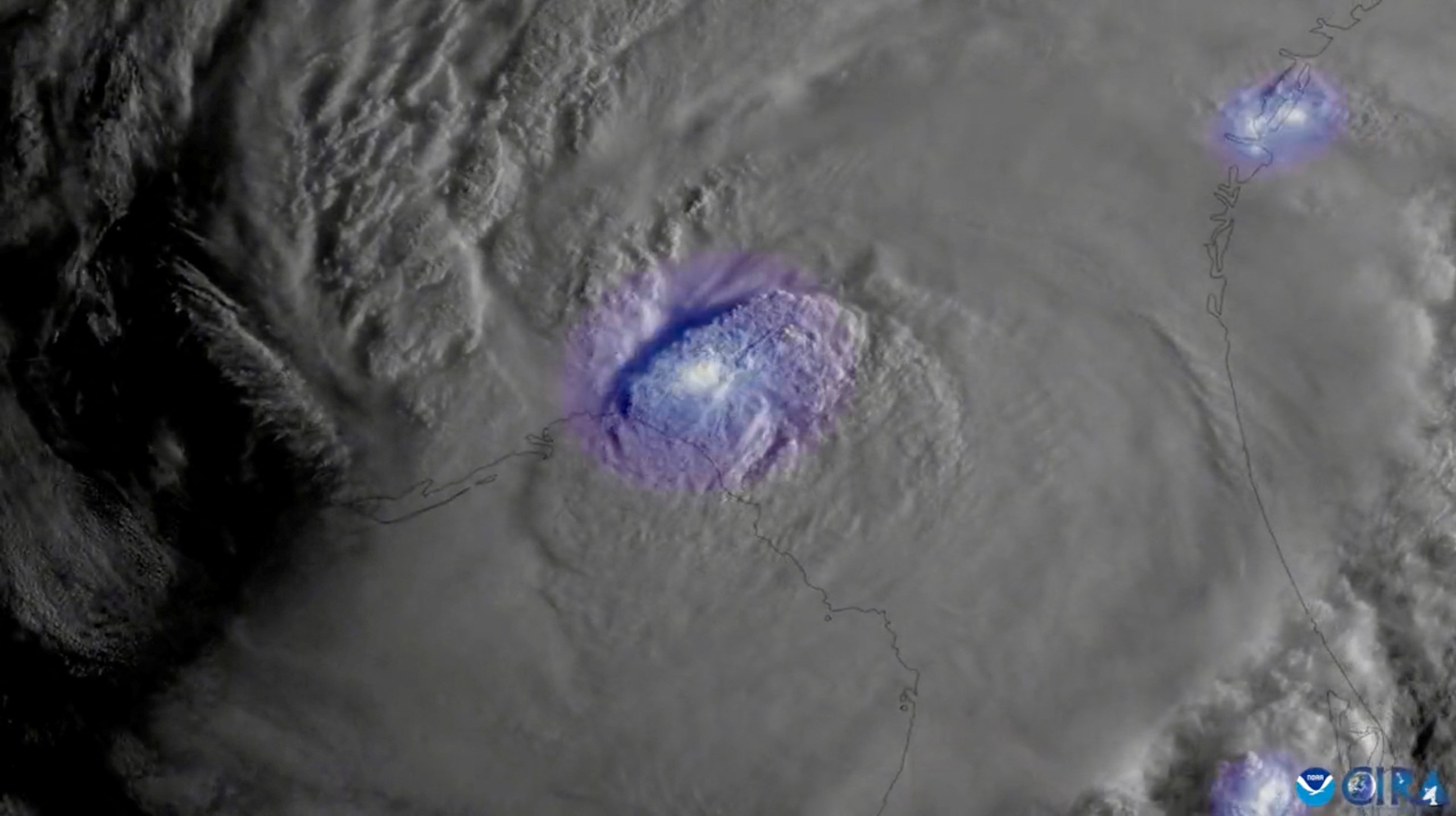 A satellite image of Hurricane Idalia, with a purple glow representing lightning.