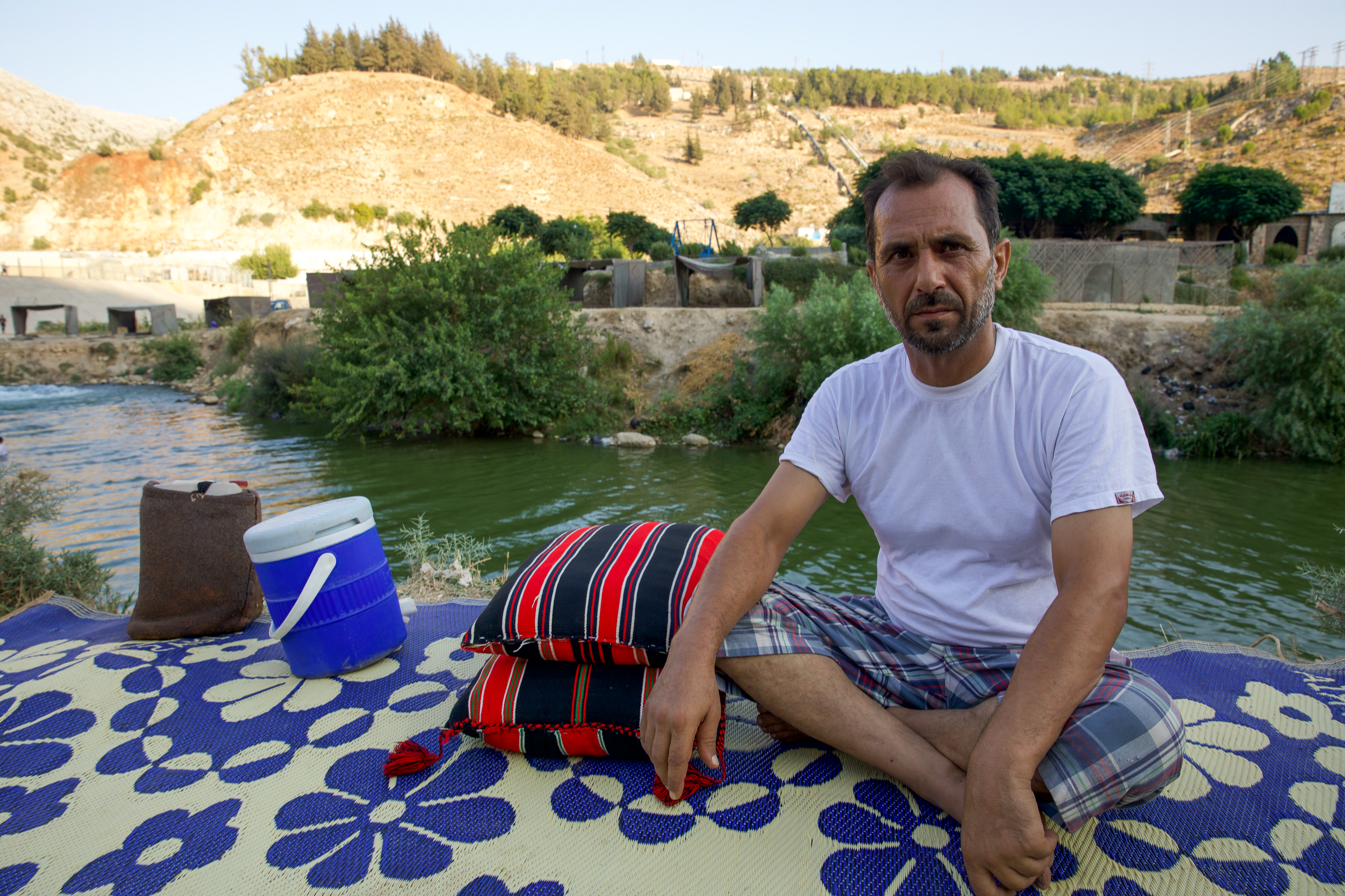 Ali al-Jaabi on the banks of al-Zarqa Spring on a plastic woven rug