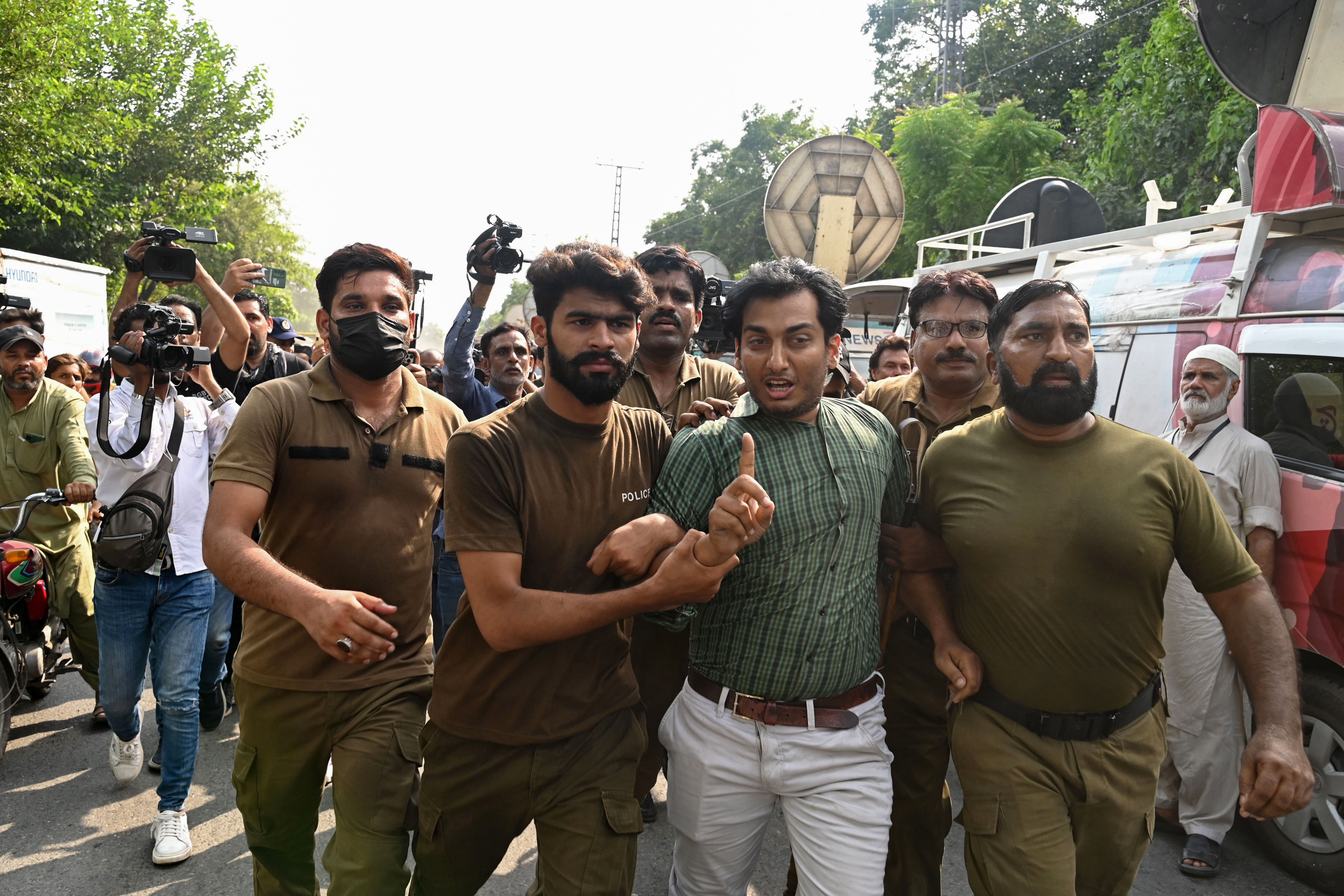 Police personnel arrest a supporter of Pakistan's former prime minister Imran Khan,
