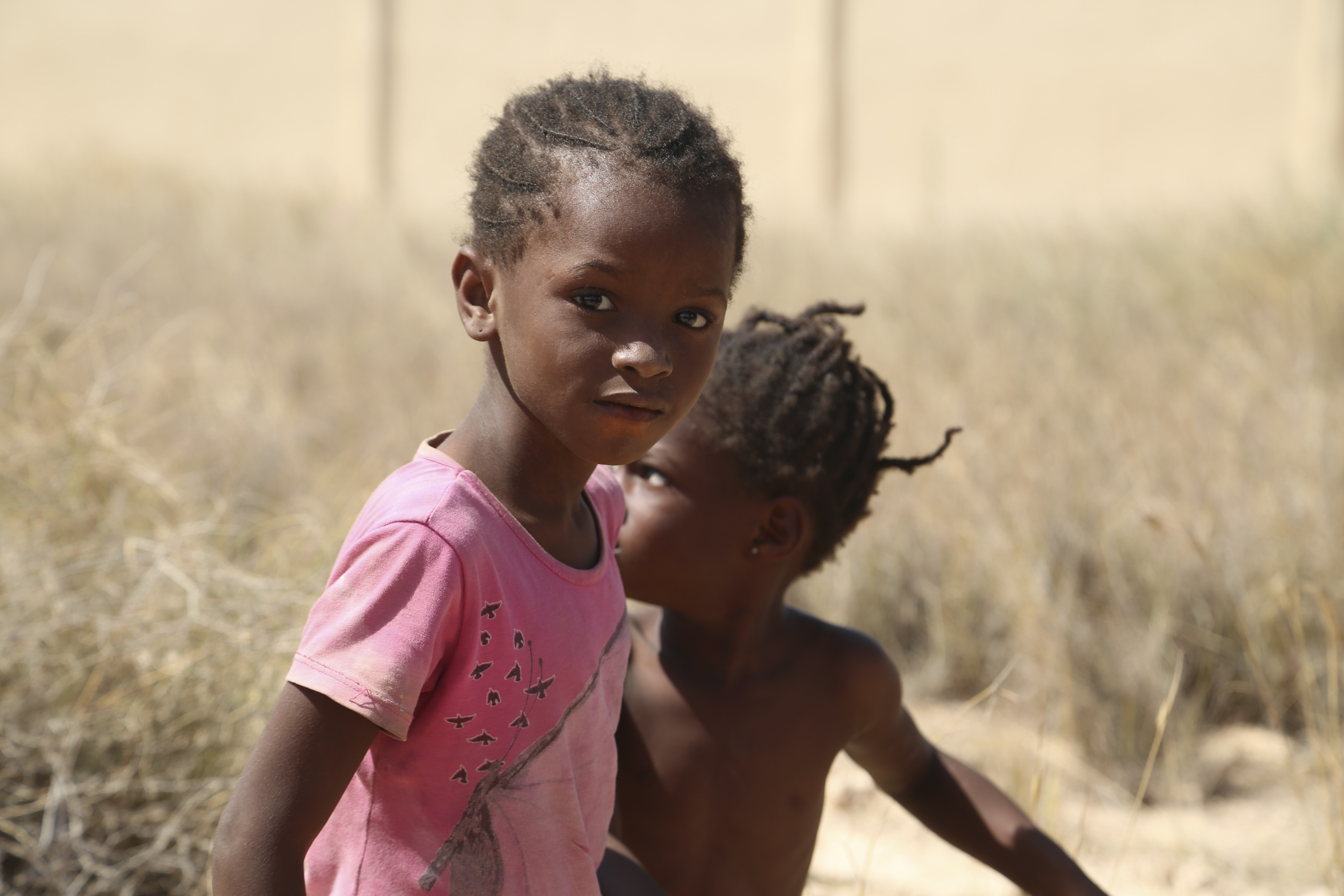 Two children look at the camera as they are stranded in the desert