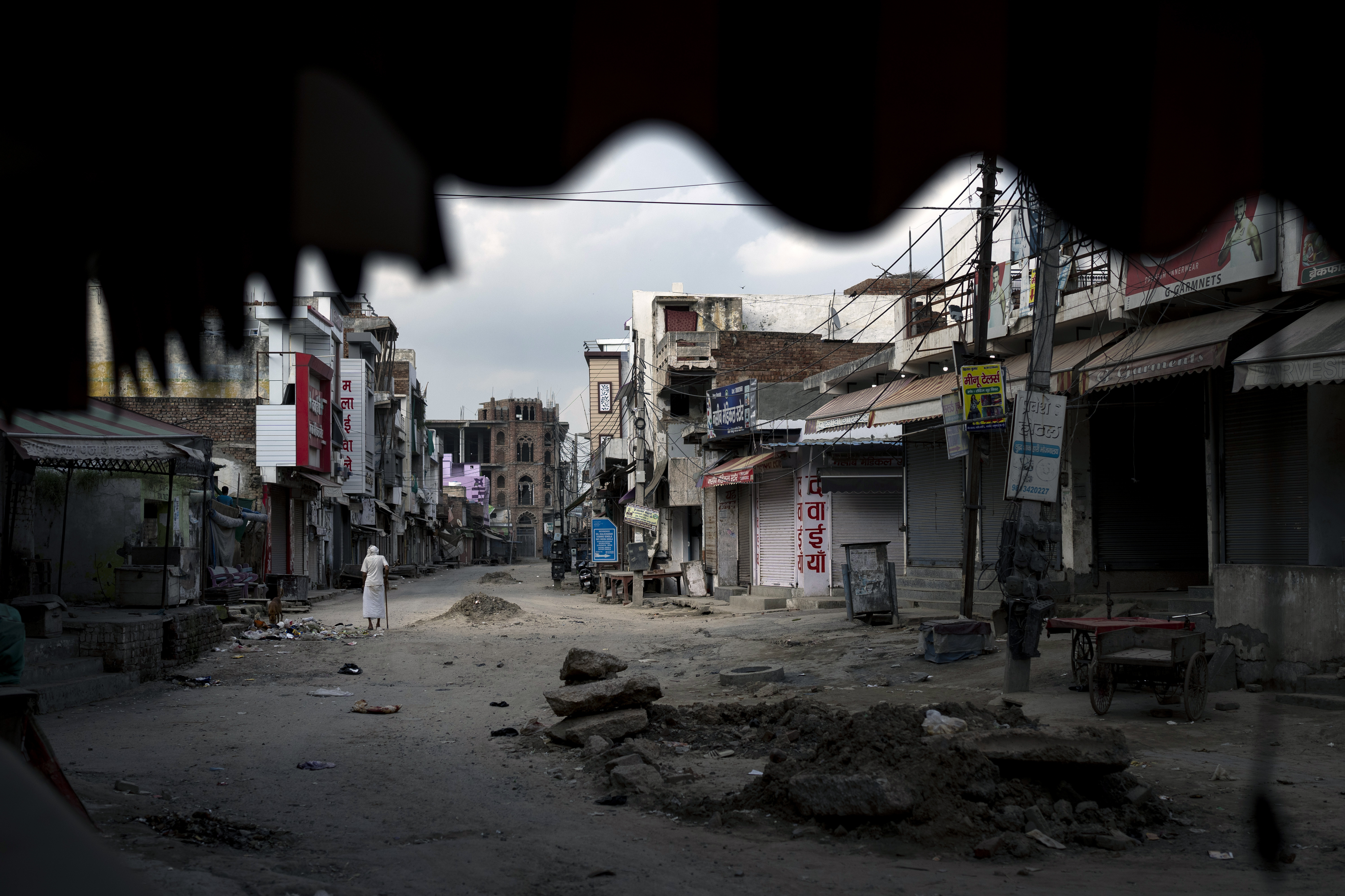 An elderly man walks in an area deserted after communal clashes in Nuh in Haryana state, India, Tuesday