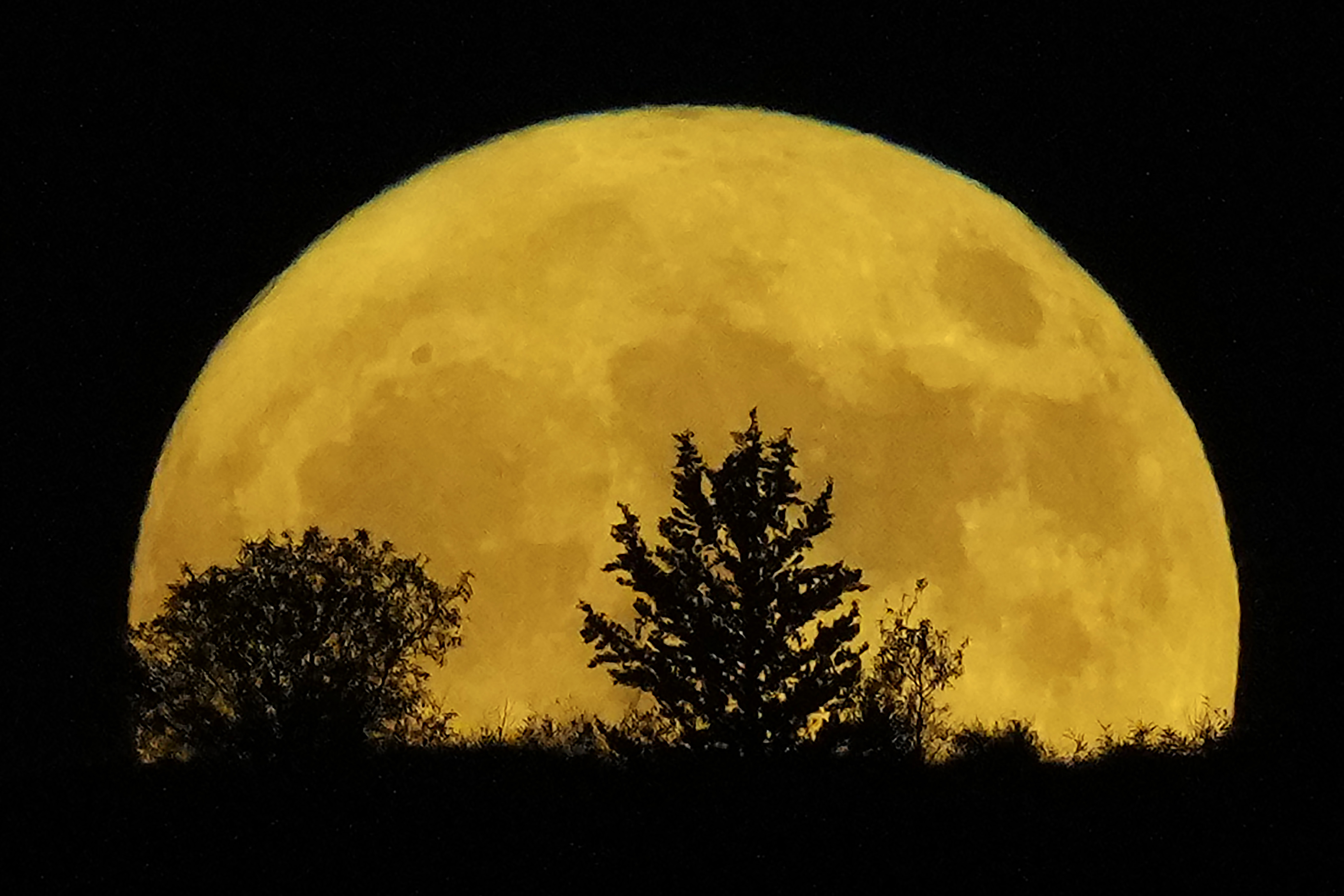 The supermoon rises behind a hill at Pera Chorio Nisou, outskirts of Nicosia, Cyprus, Tuesday, Aug. 1, 2023.