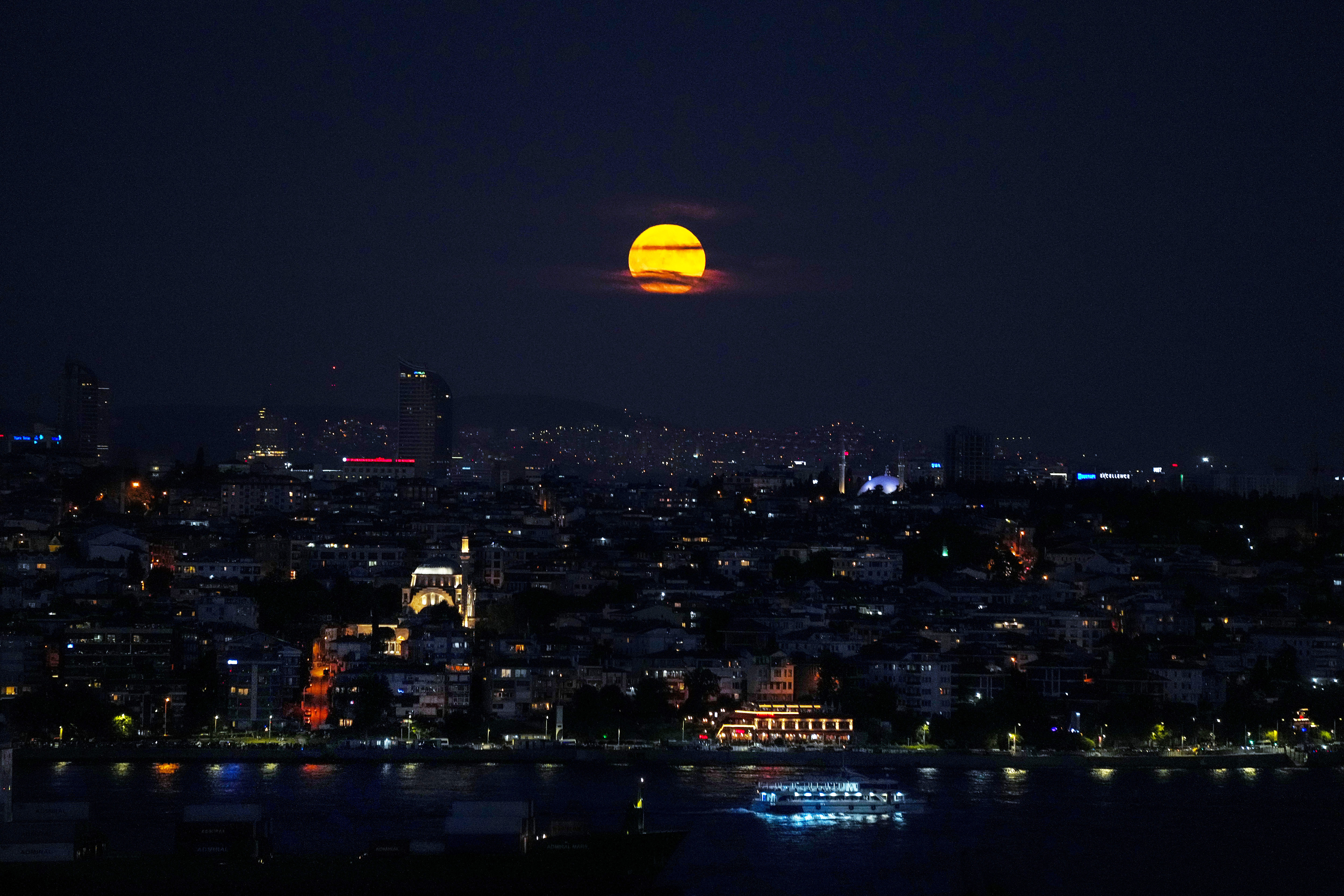 The supermoon rises in the sky as ferries and cargo ships cross the Bosphorus in Istanbul, Turkey