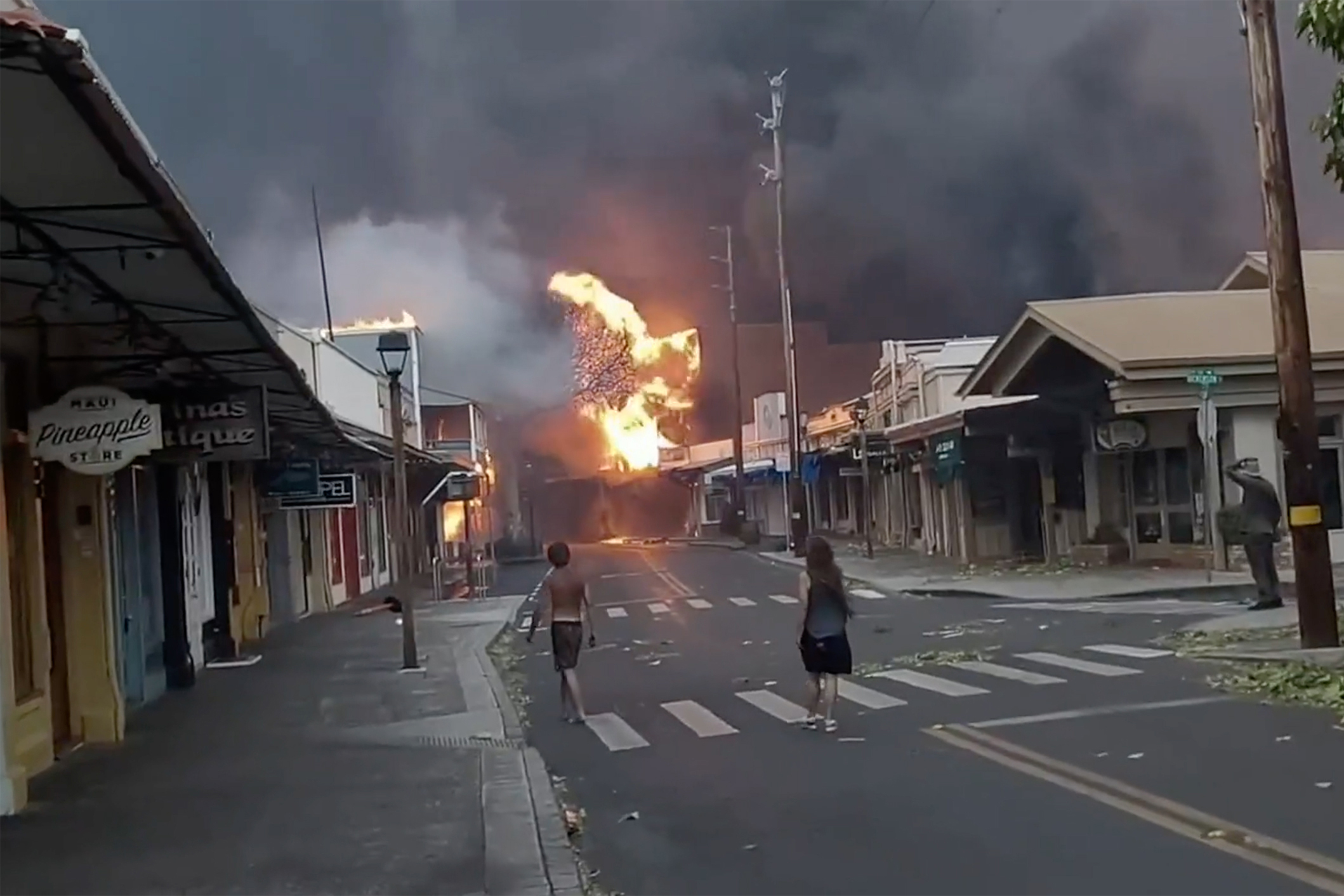 People watch as smoke and flames fill the air from raging wildfires on Front Street in downtown Lahaina, Maui