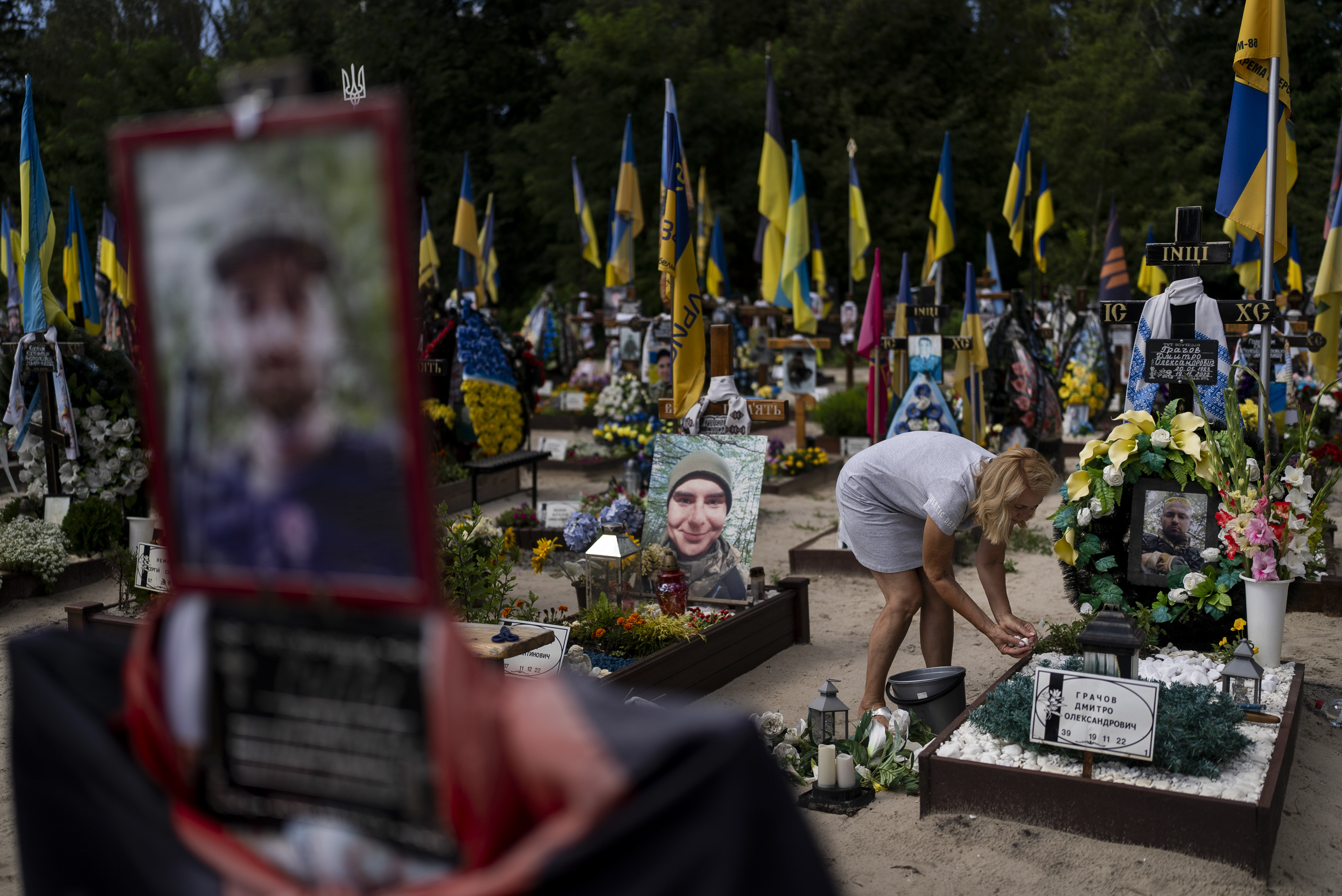 A woman tends to the grave of her son, a Ukrainian soldier who was killed in the war against Russia, in Kyiv, Ukraine.