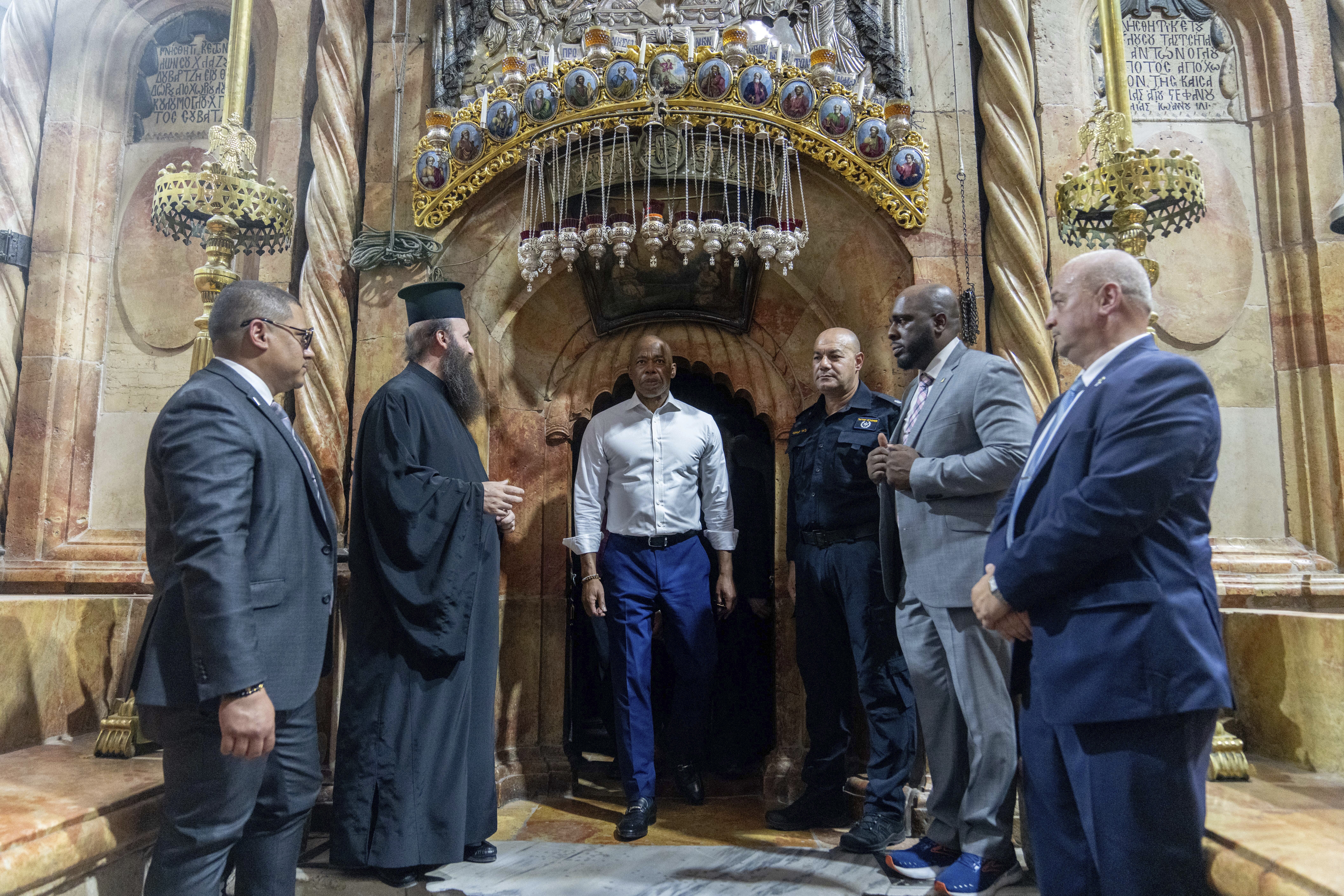 With religious leaders and staff around him, Eric Adams steps out of a doorway at the Church of the Holy Sepulcher.