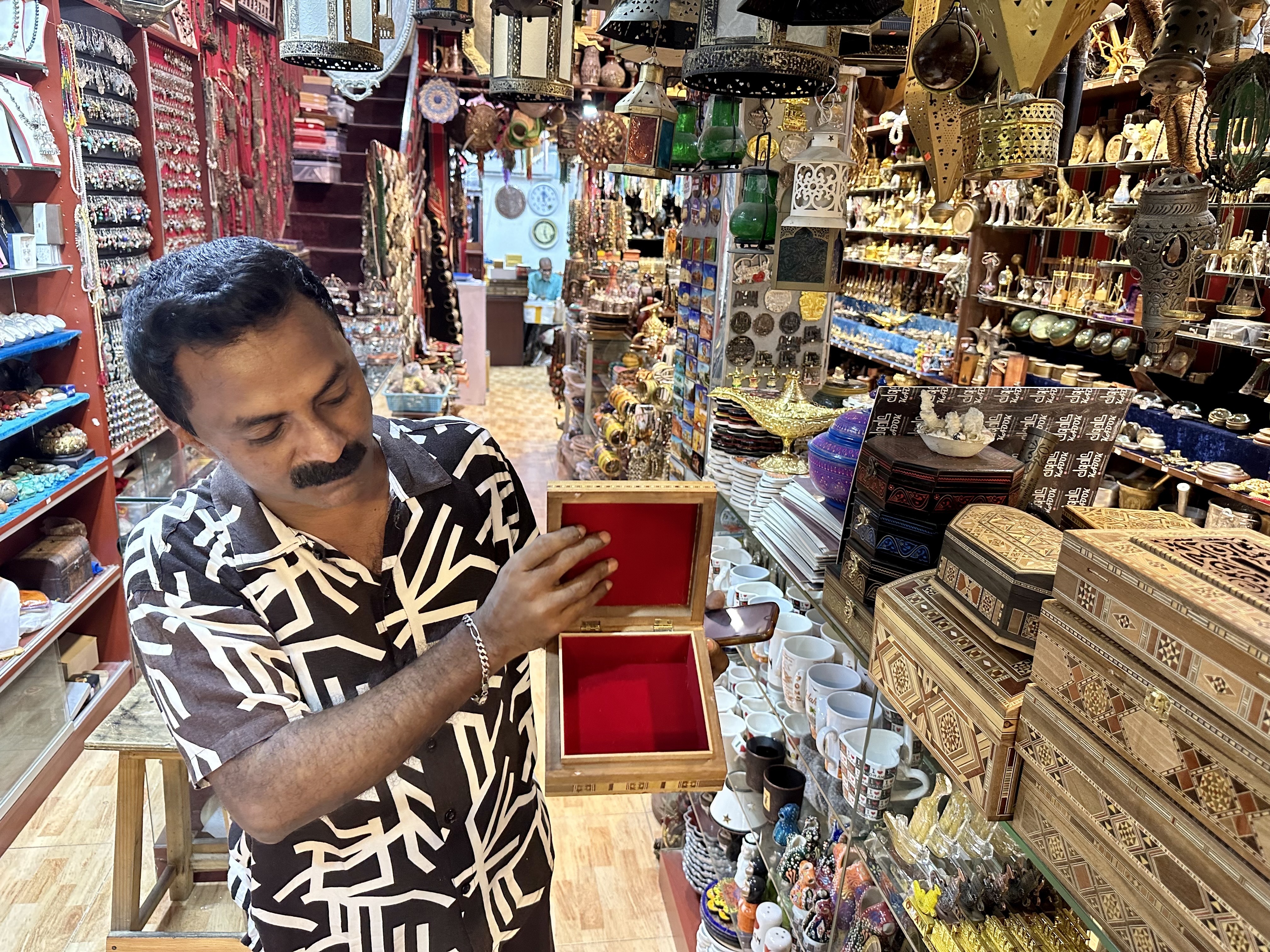 Razzaq shows an engraved wooden box for sale in the one of the shops he works in