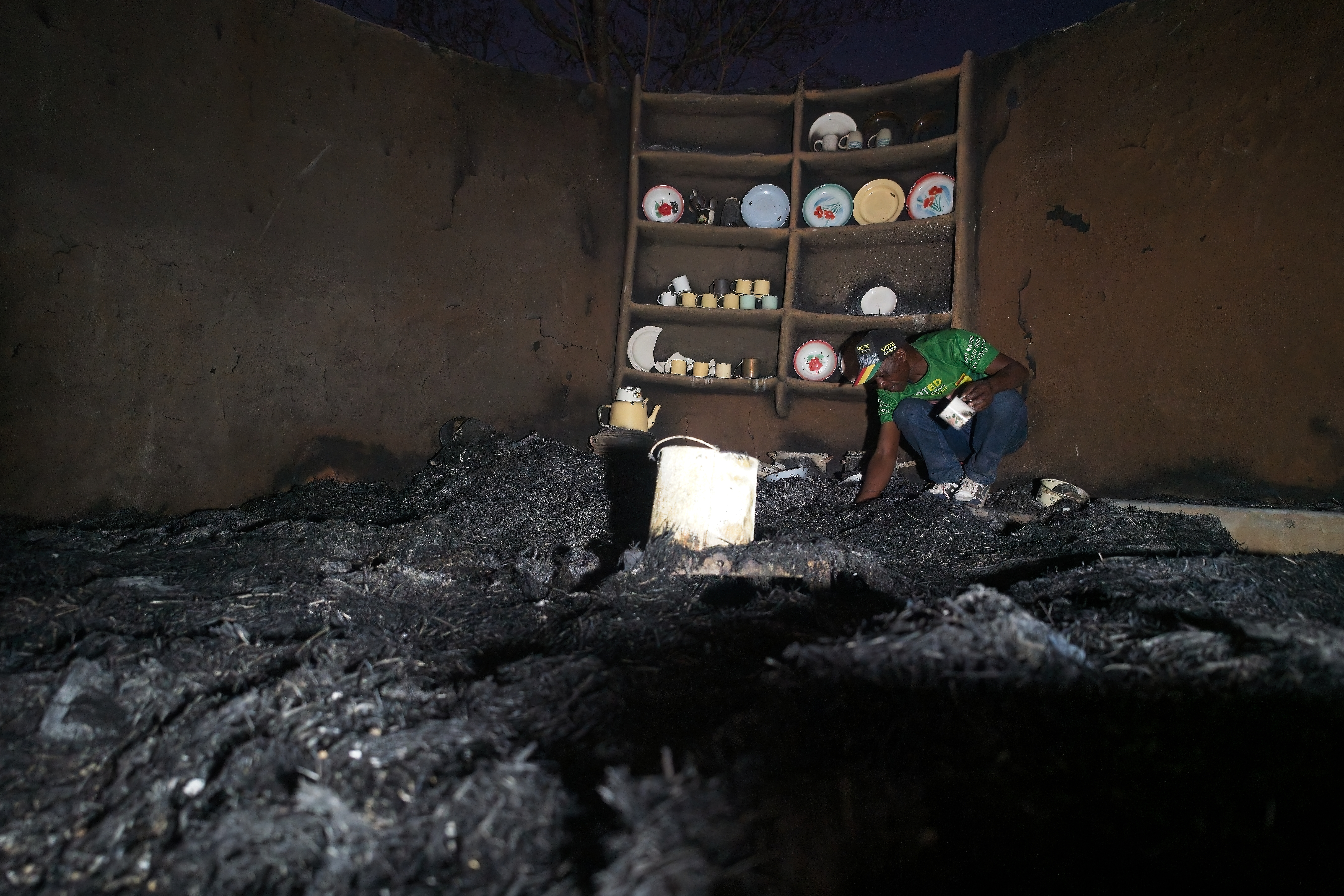 Shepherd Mahove, 48, looks through the ashes of his burnt kitchen at his homestead in Hanke B Village, Zimbabwe
