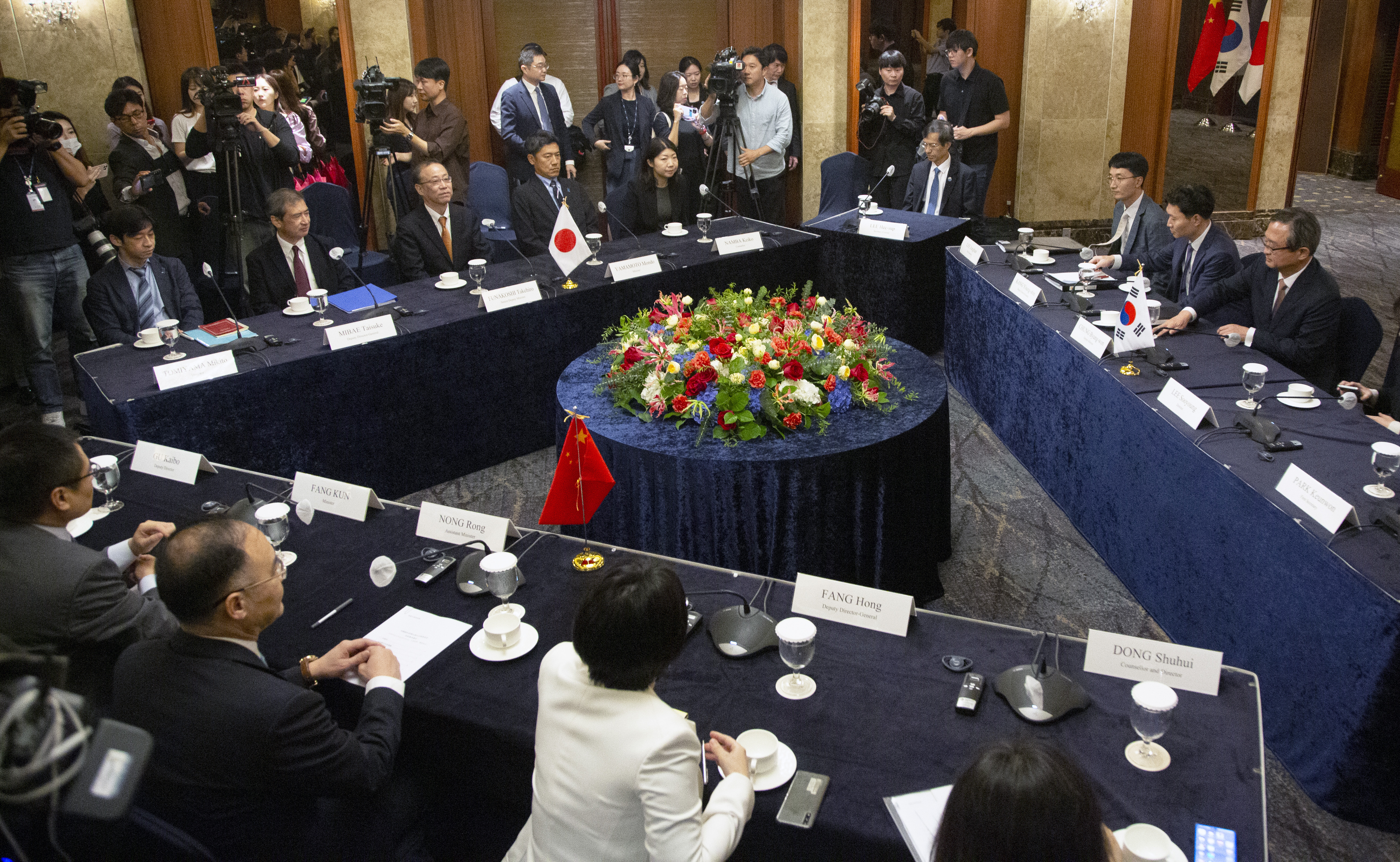 The officials sitting around the discussion table. The tables are positioned in a rectangle. There are some flags in the background.