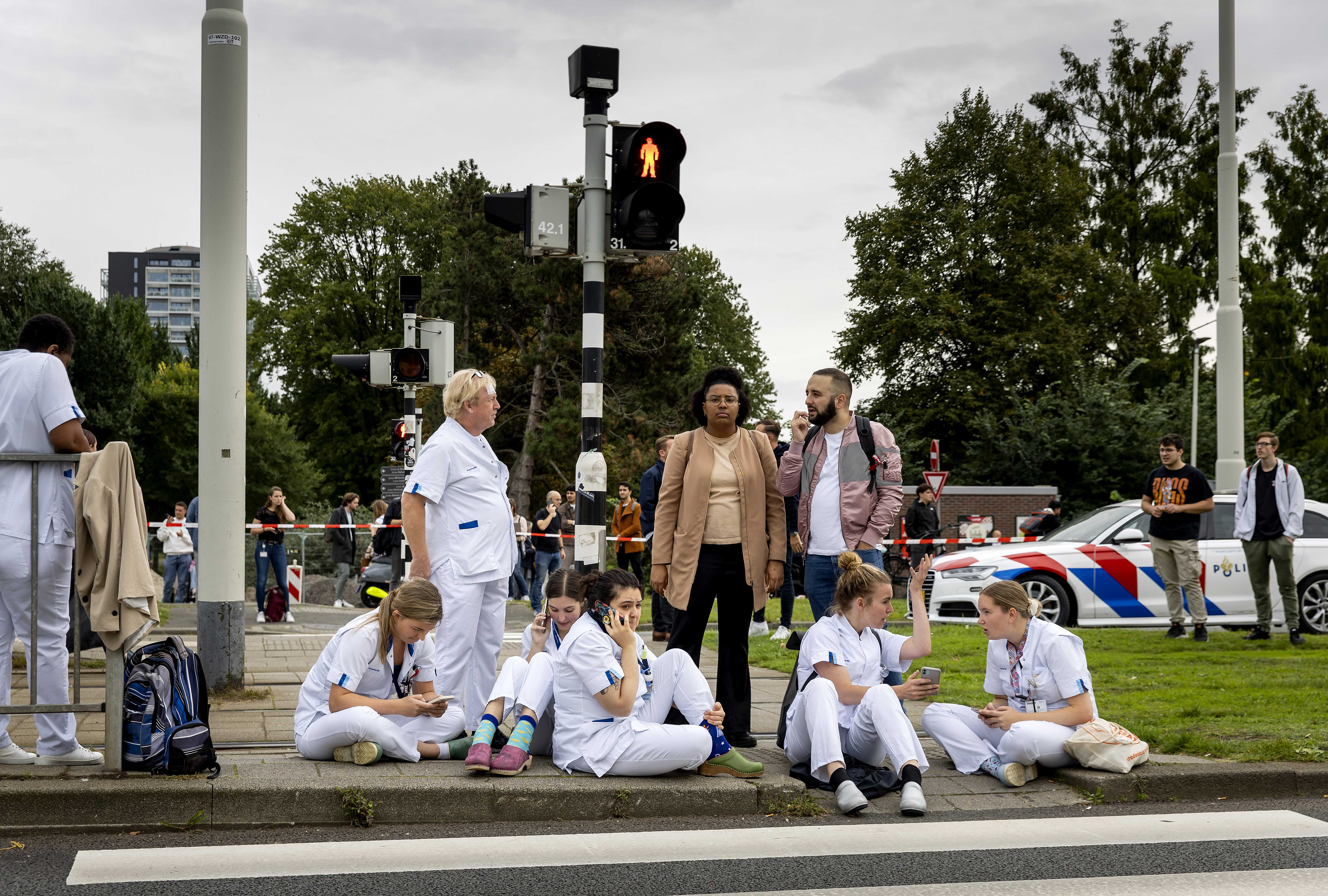Medical staff wait outside the Erasmus MC Rotterdam hospital on Rochussenstraat, which has been cordoned off after two shooting incidents in Rotterdam, Netherlands