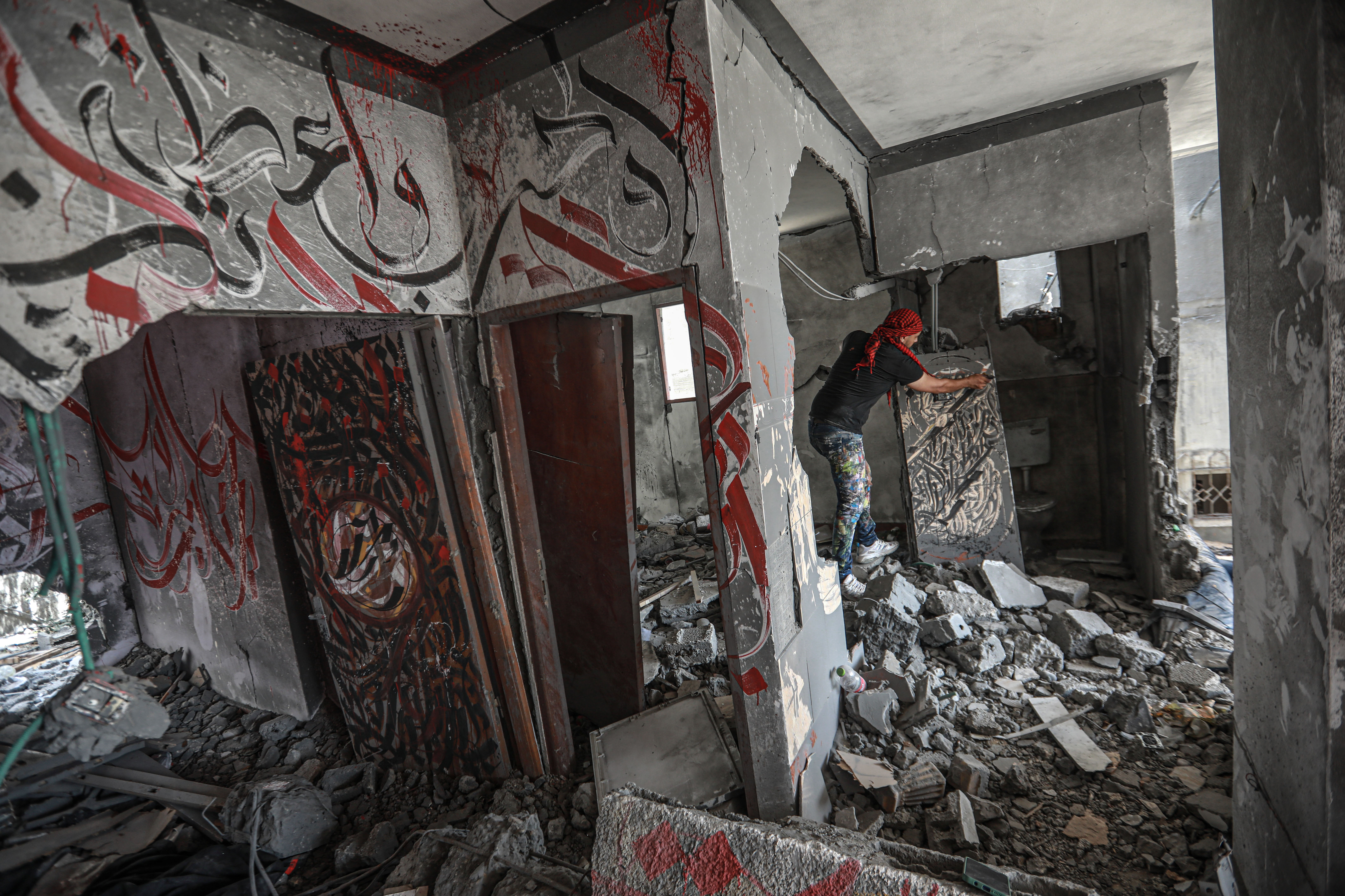 Ayman standing on a mountain of rubble in a home, working