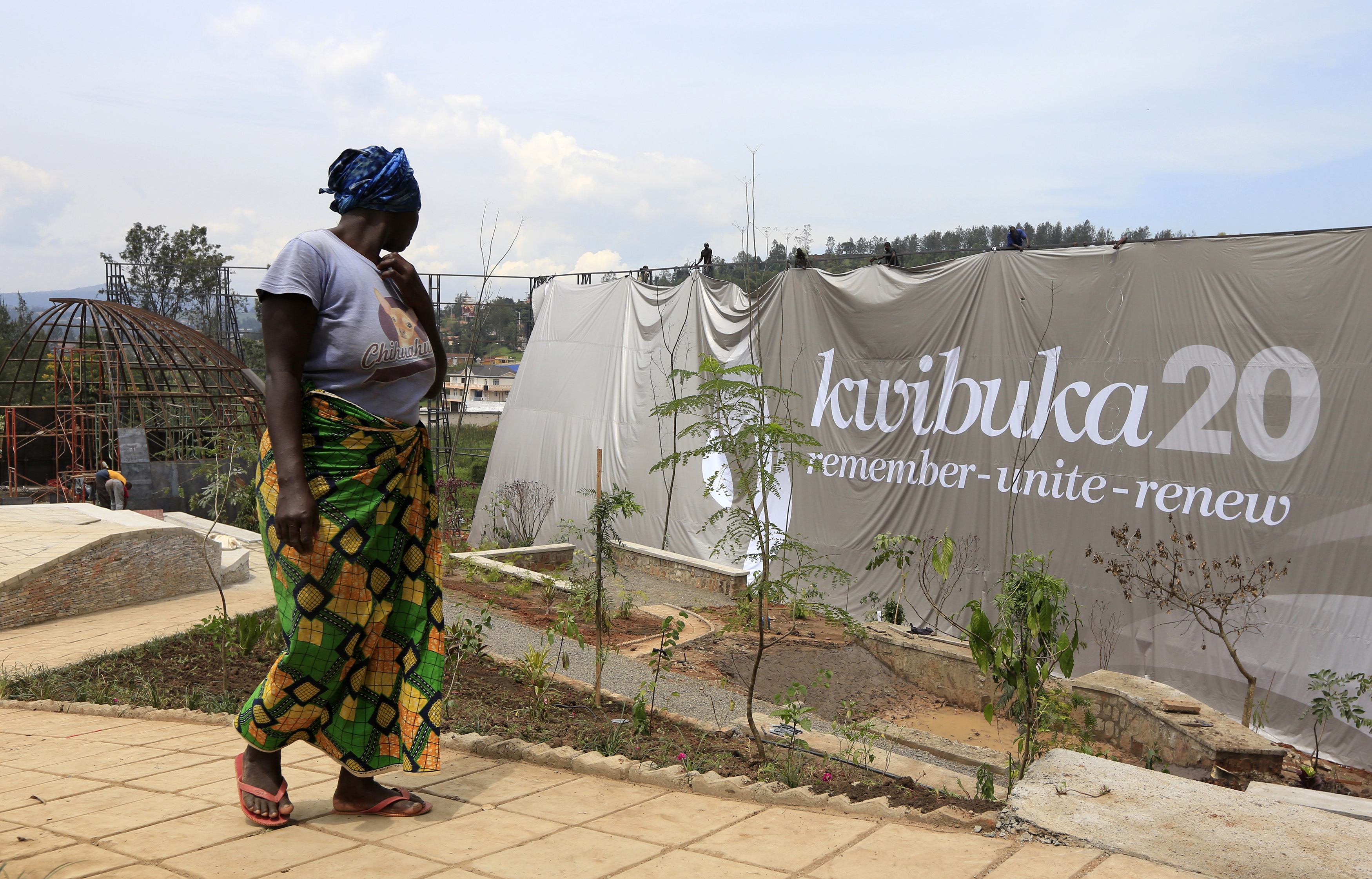 A labourer walks past a banner that reads "Remembering 20 years" at the Kigali Genocide Memorial grounds as the country prepares to commemorate the 20th anniversary of the 1994 Rwandan Genocide in the capital Kigali in April 2014