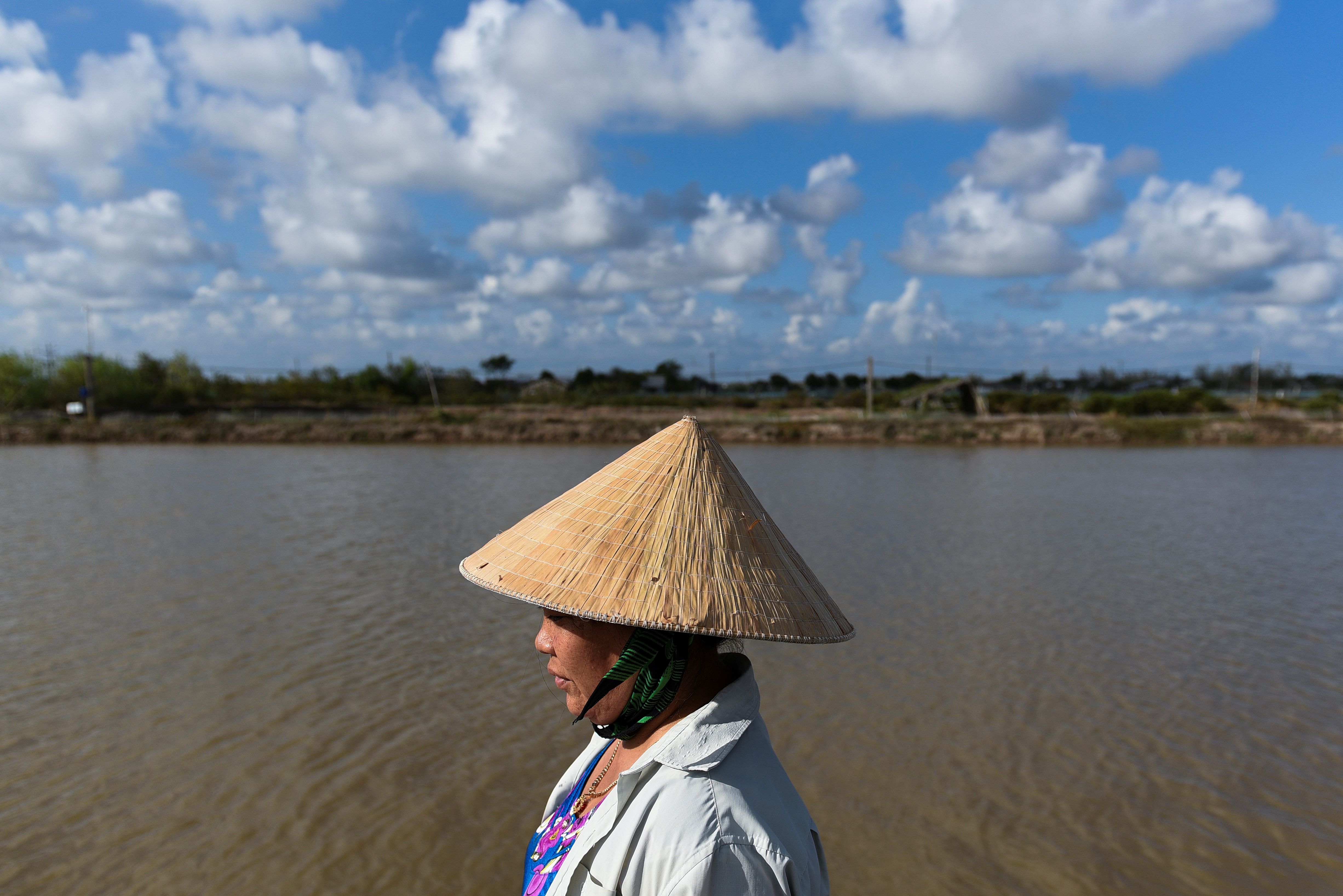 A Vietnamese farmer walking past a lake that was once a rice field